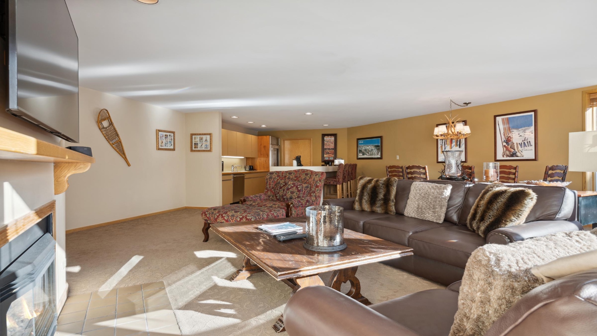 Unwind in your spacious living area where plush leather sofas invite relaxation, natural light dances across wood finishes, and mountain-inspired decor creates the perfect alpine retreat atmosphere.