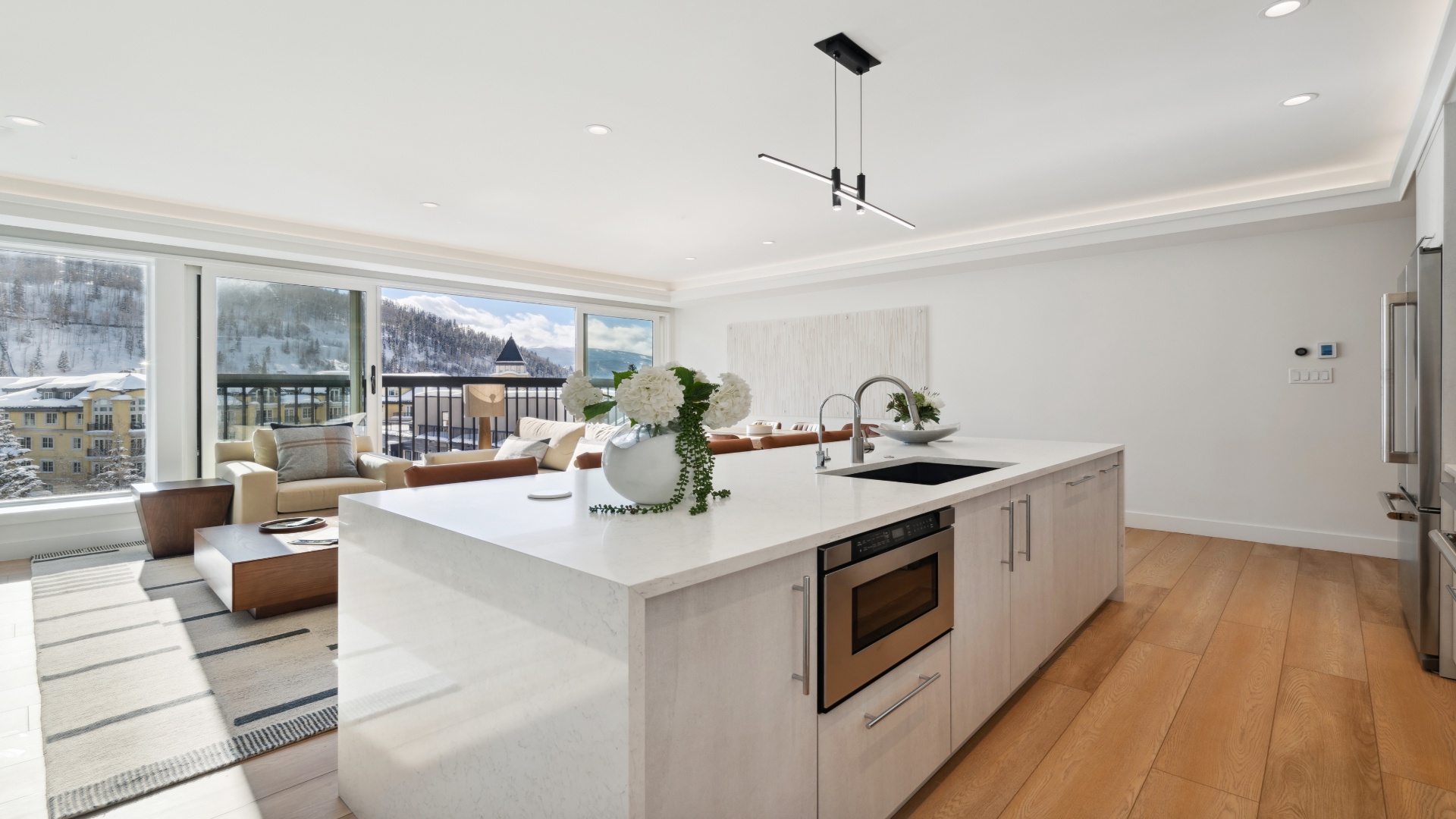 Your modern chef's kitchen flows seamlessly into the living space, where snowy mountain views frame your alpine retreat. Sleek countertops and stainless-steel appliances make cooking a pleasure.