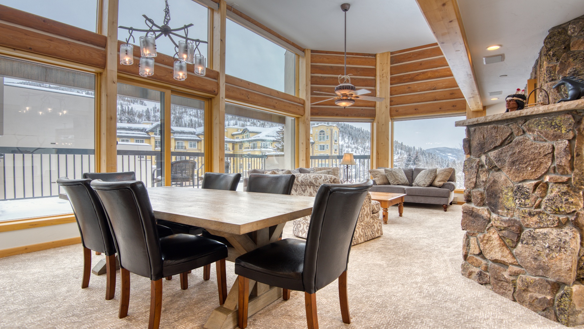 Gather around the solid wood dining table and take in stunning mountain views through floor-to-ceiling windows. Your open-concept living space features a cozy stone fireplace, perfect for après-ski relaxation.