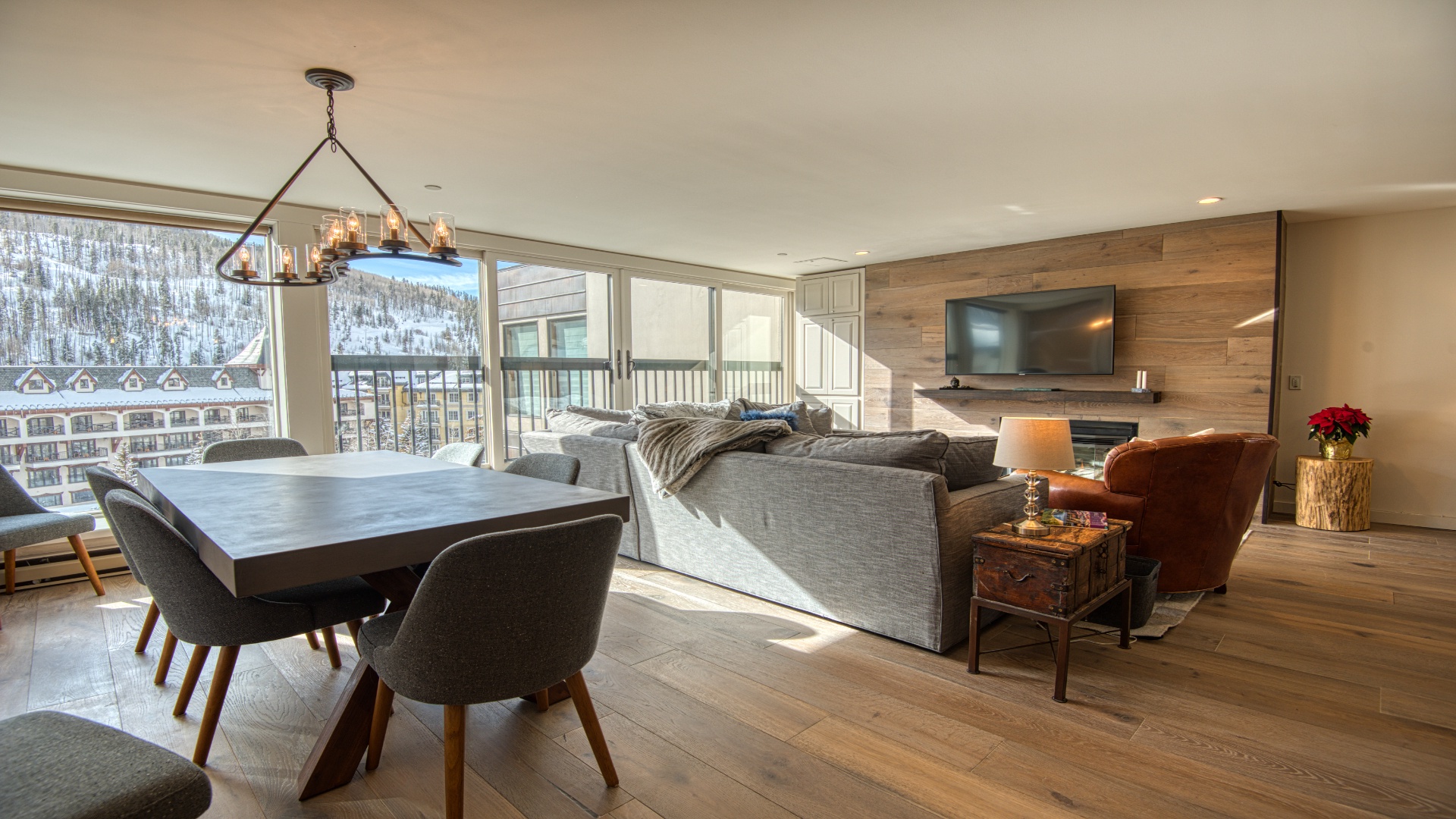 Sunlight floods your open-concept space, where rustic charm meets mountain elegance. Cozy up on plush seating by the fireplace or gather at the sleek dining table, all while savoring snowy alpine views through floor-to-ceiling windows.