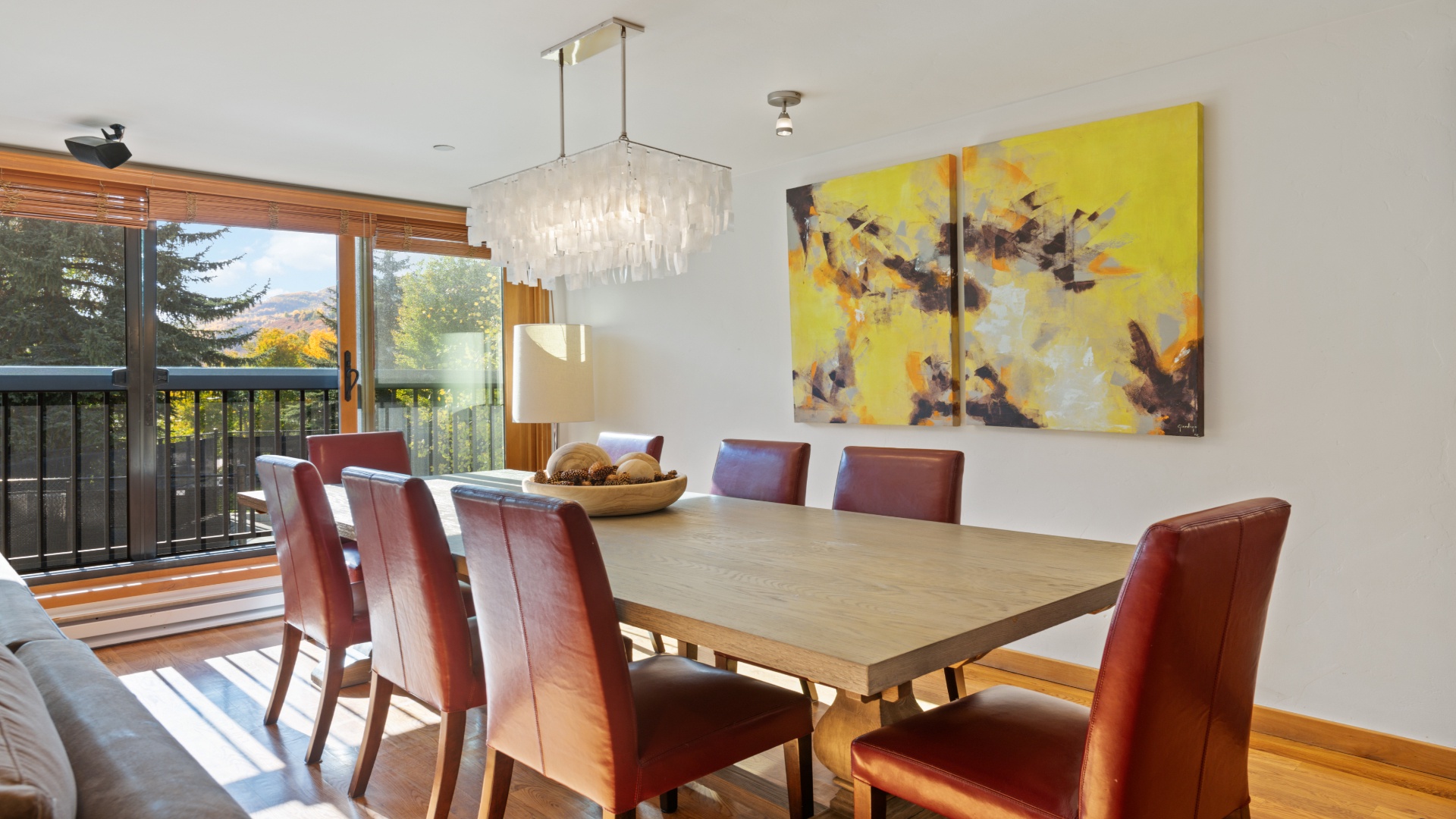 Gather around this beautifully crafted dining table where memorable meals await. The elegant chandelier sets a warm ambiance while mountain views through the balcony doors create your perfect backdrop.