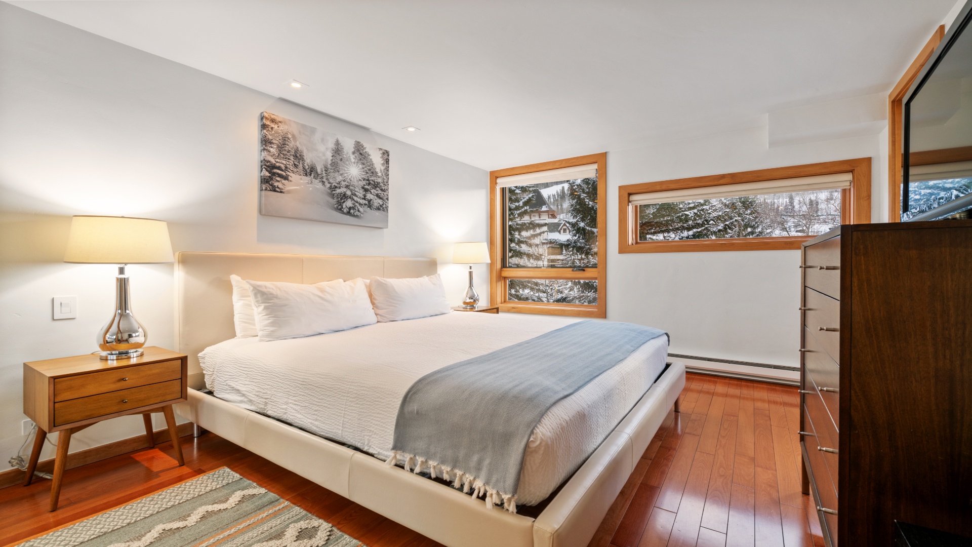 Wake up to crisp mountain views framed by warm wood windows. Your private retreat features a plush king bed, cozy bedside lighting, and a serene winter landscape awaiting you each morning.