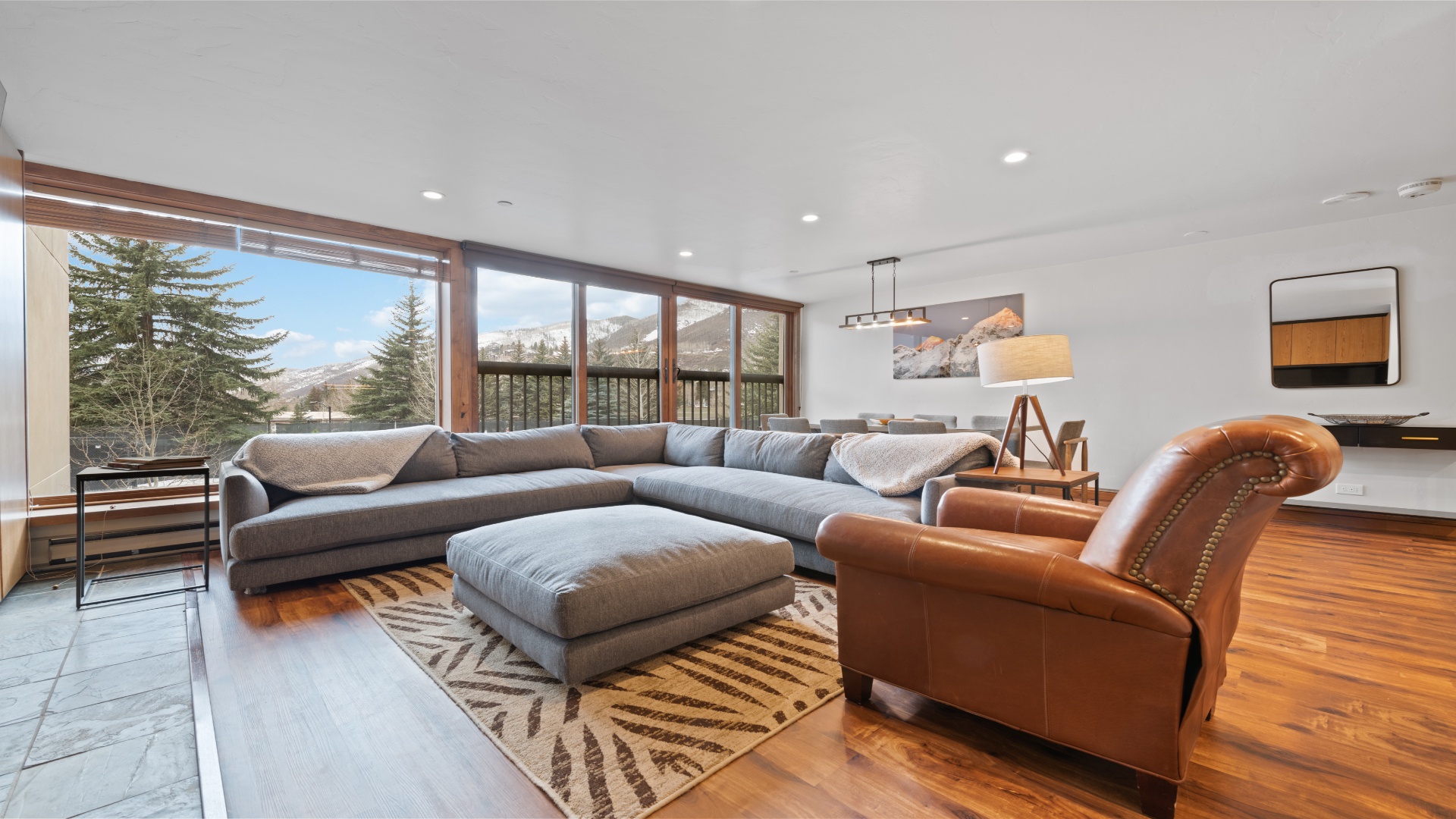 Your spacious living room welcomes you with mountain views framed by expansive windows, plush seating for everyone, and warm wood accents that create the perfect retreat.