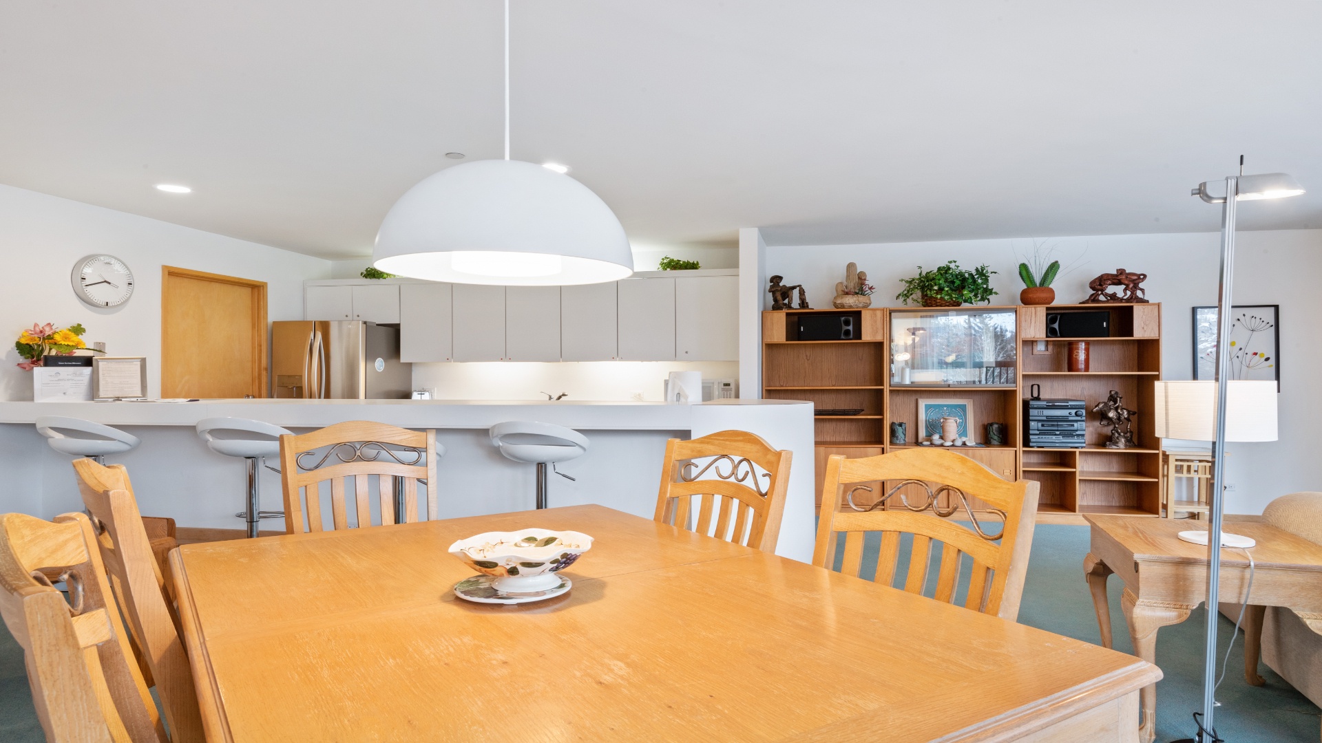 An inviting open-concept space with a warm wooden dining table where you can gather for meals, and a modern kitchen with a bright breakfast bar for casual moments together.