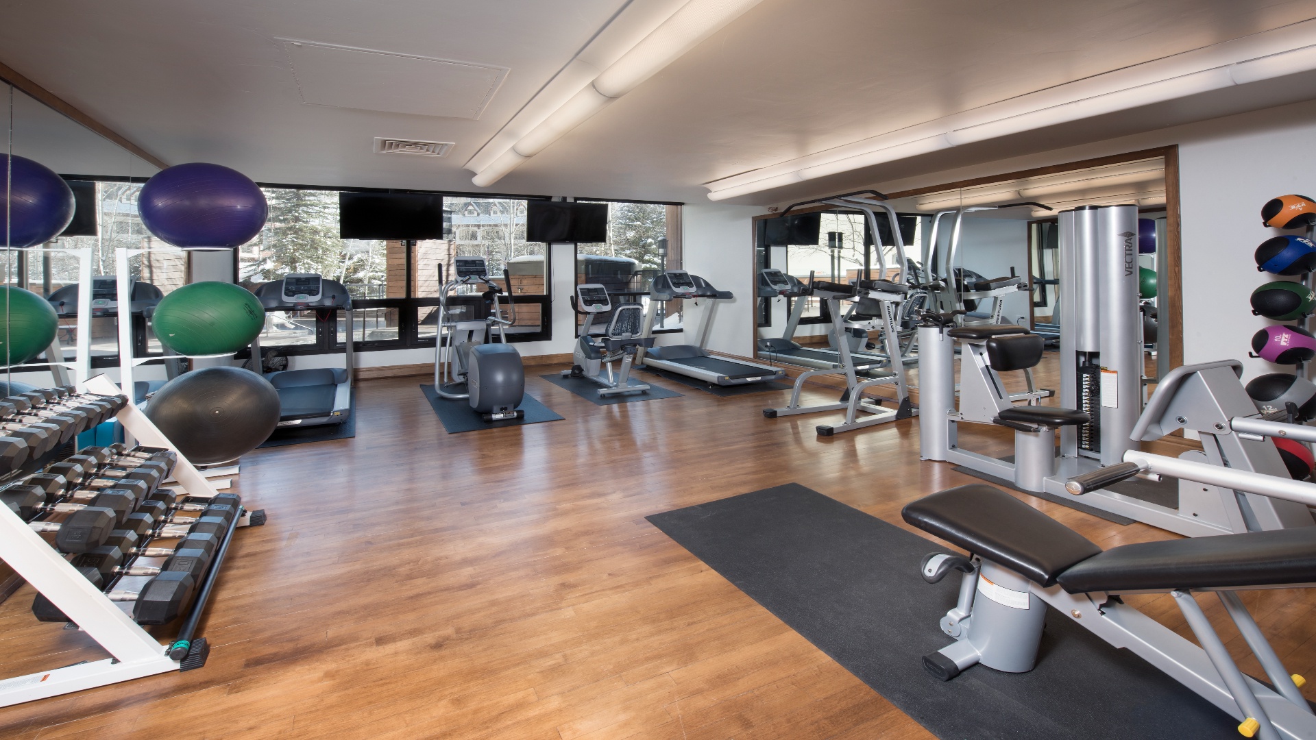 Modern fitness center with cardio machines, free weights, and strength equipment overlooking scenic mountain views—perfect for staying active during your stay.
