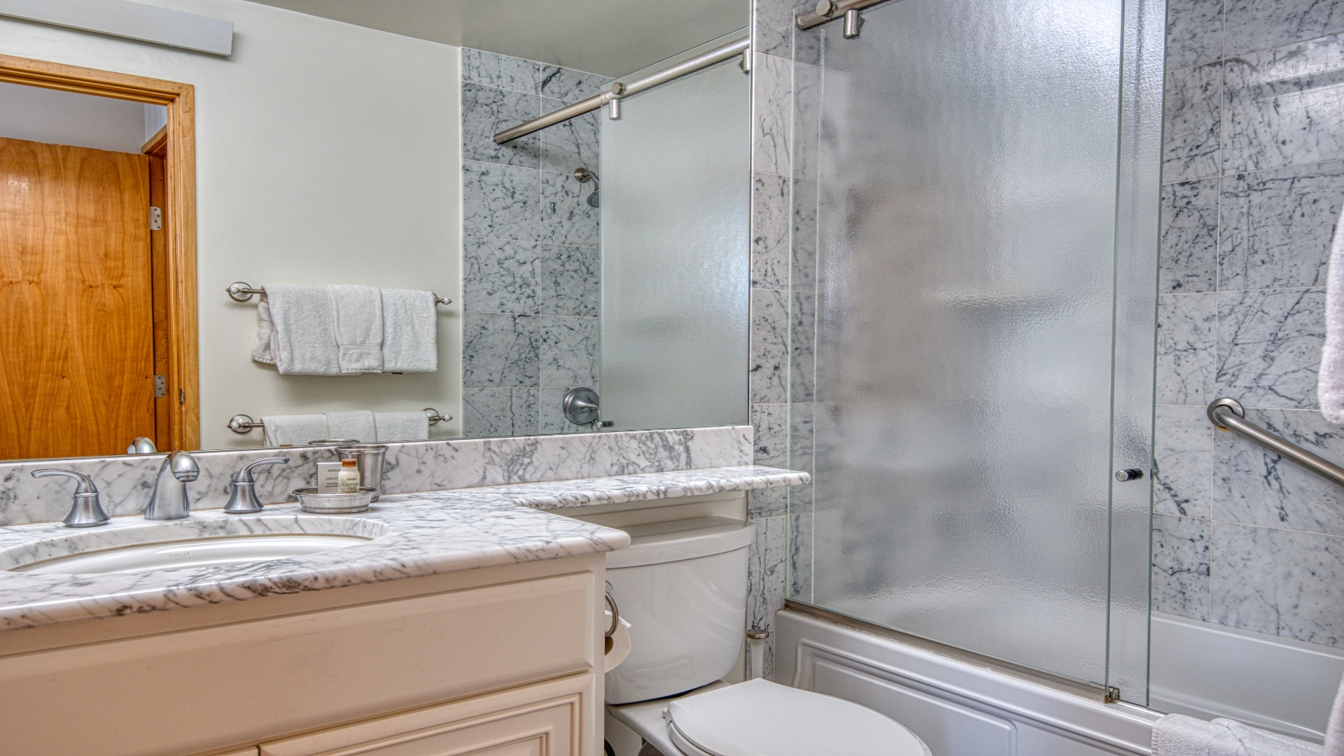Freshen up in this elegant marble bathroom, complete with a glass-enclosed shower, dual vanity, and plush towels—your private retreat after a day exploring.
