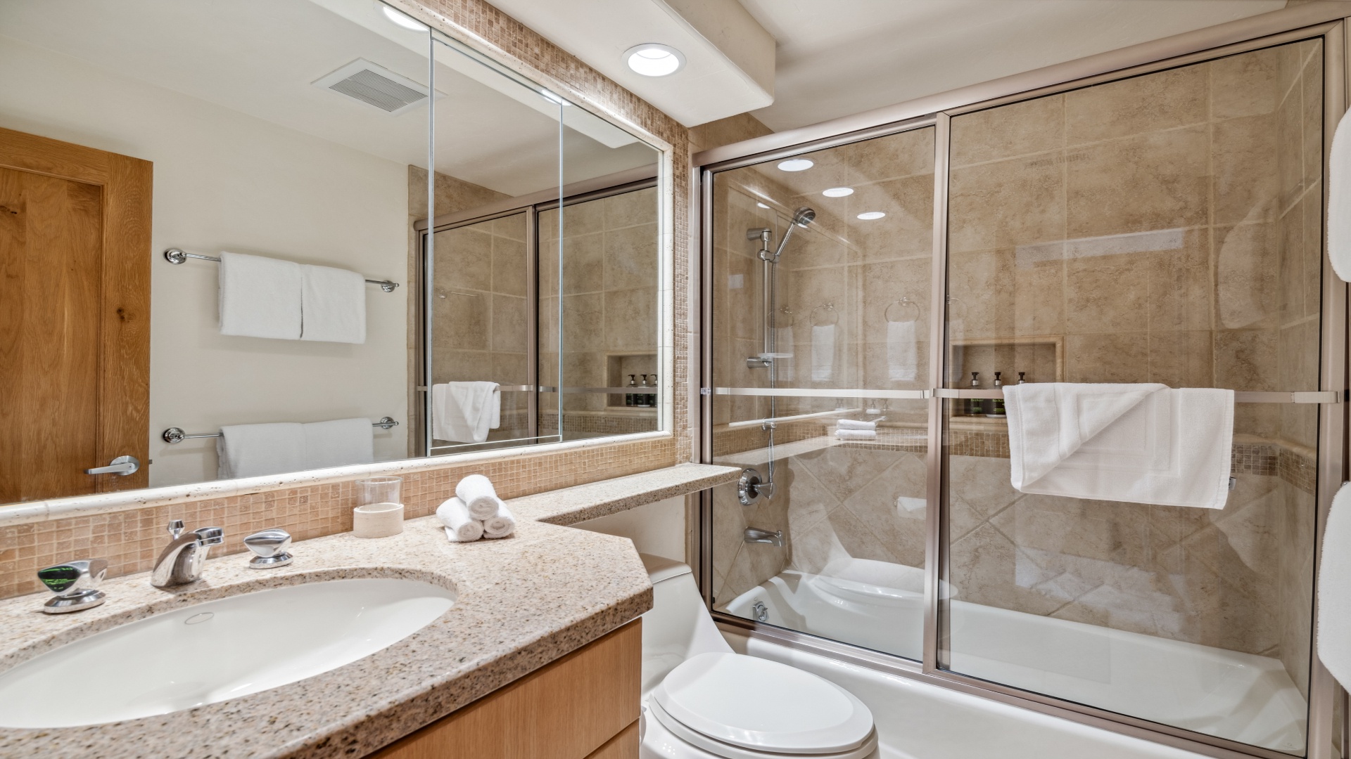 Step into your private spa-like bathroom with granite counters, walk-in shower, plush towels, and warm wood accents creating a peaceful retreat.
