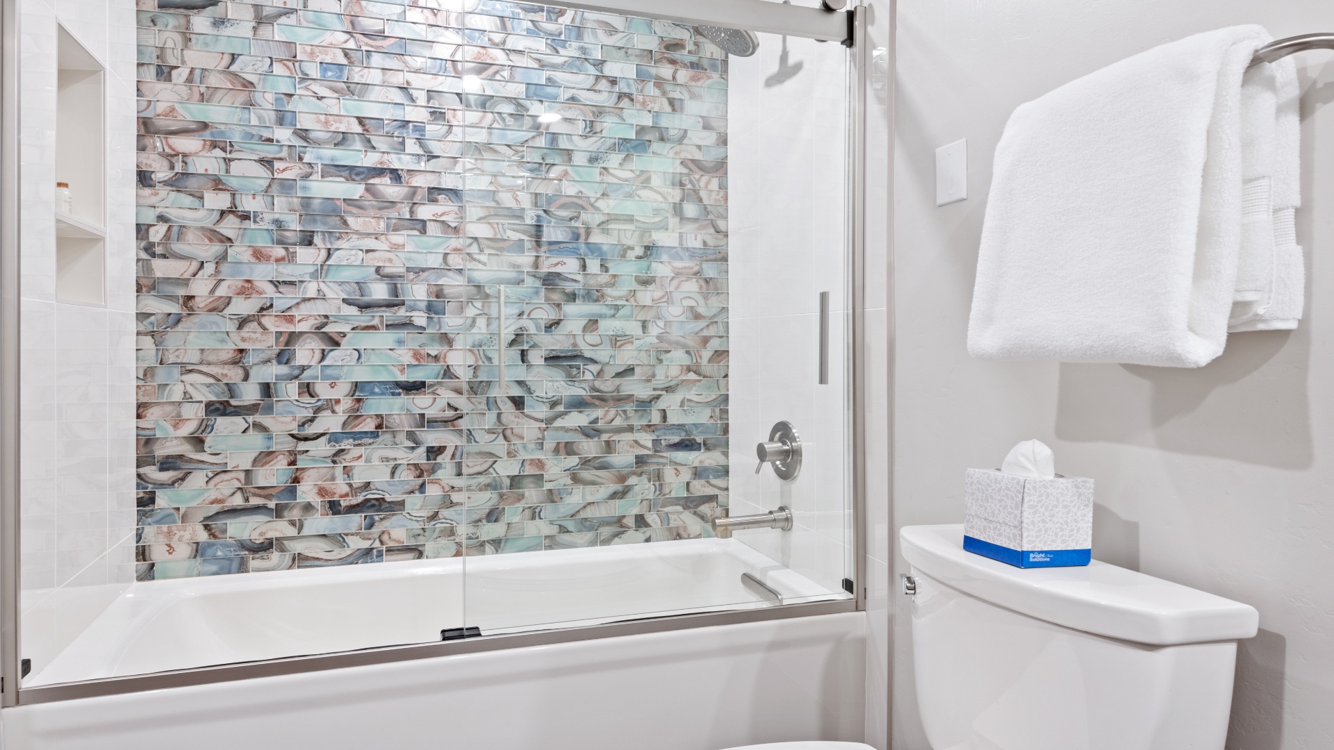 Unwind in your modern bathroom with a gorgeous mosaic tile wall that adds coastal elegance to your relaxing soak. Fresh towels and thoughtful touches make it feel like home.