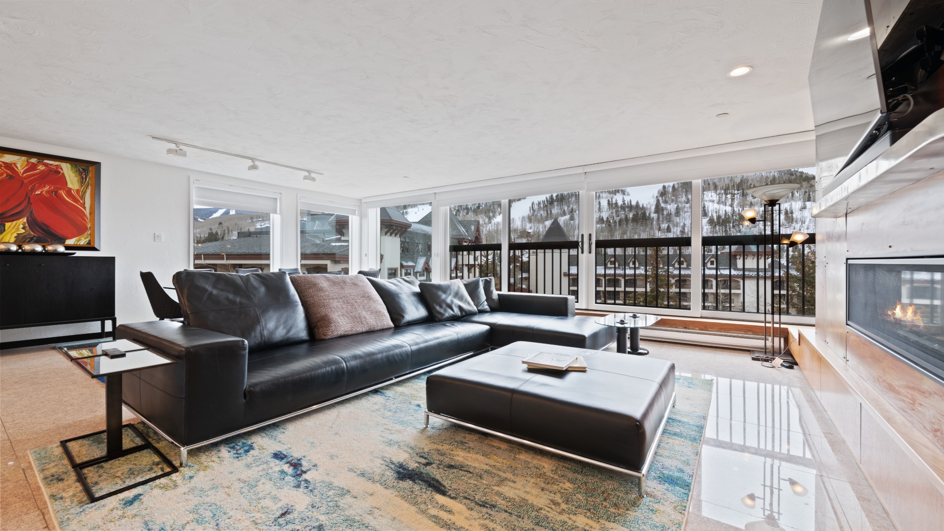 Relax in your sleek living space with floor-to-ceiling windows framing breathtaking snow-dusted mountain views. Sink into plush leather seating by the warm fireplace after a day on the slopes.