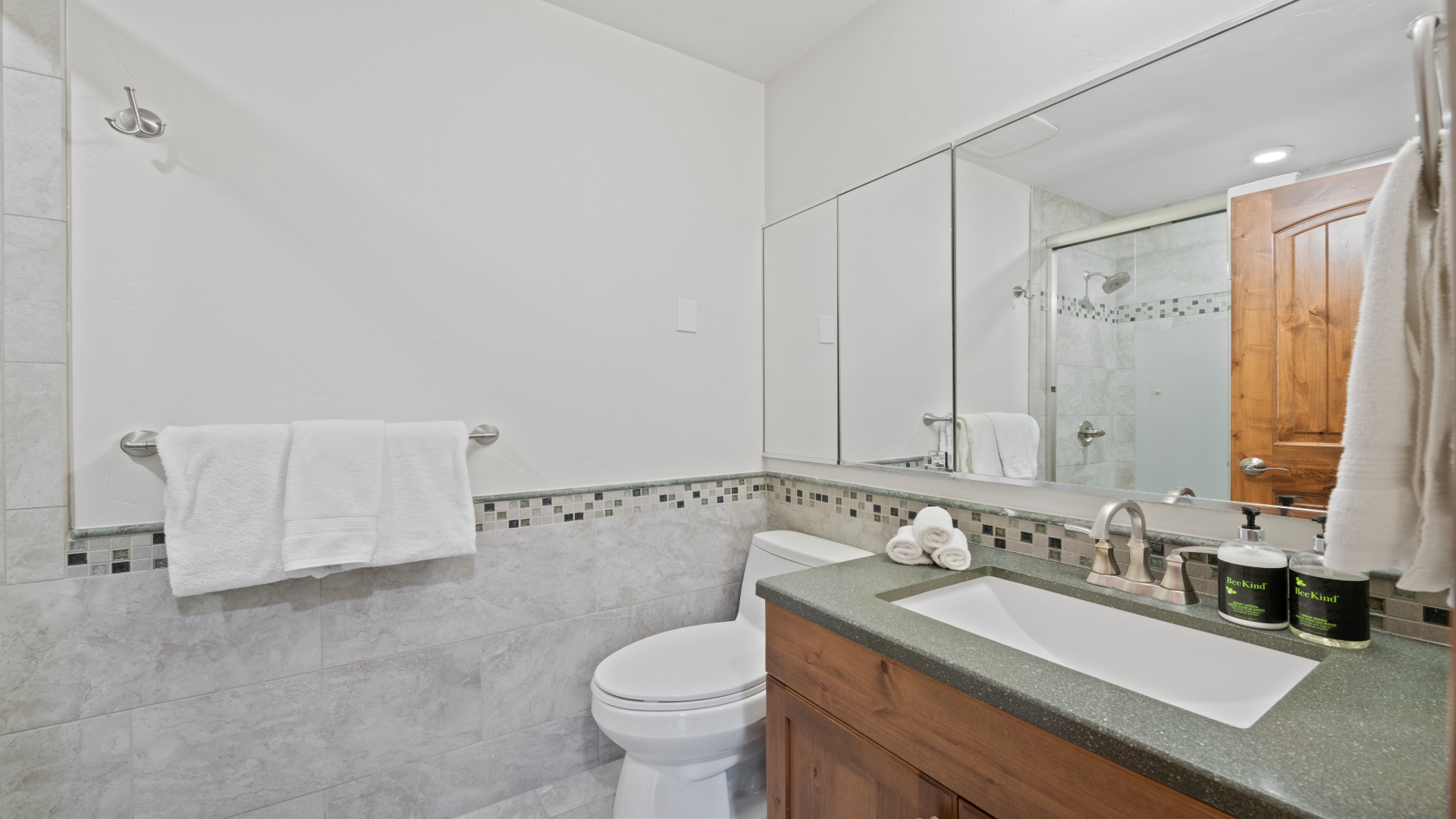 Step into your private spa-like retreat with a walk-in shower, fresh towels, and stylish mosaic tile accents creating a serene, modern atmosphere.