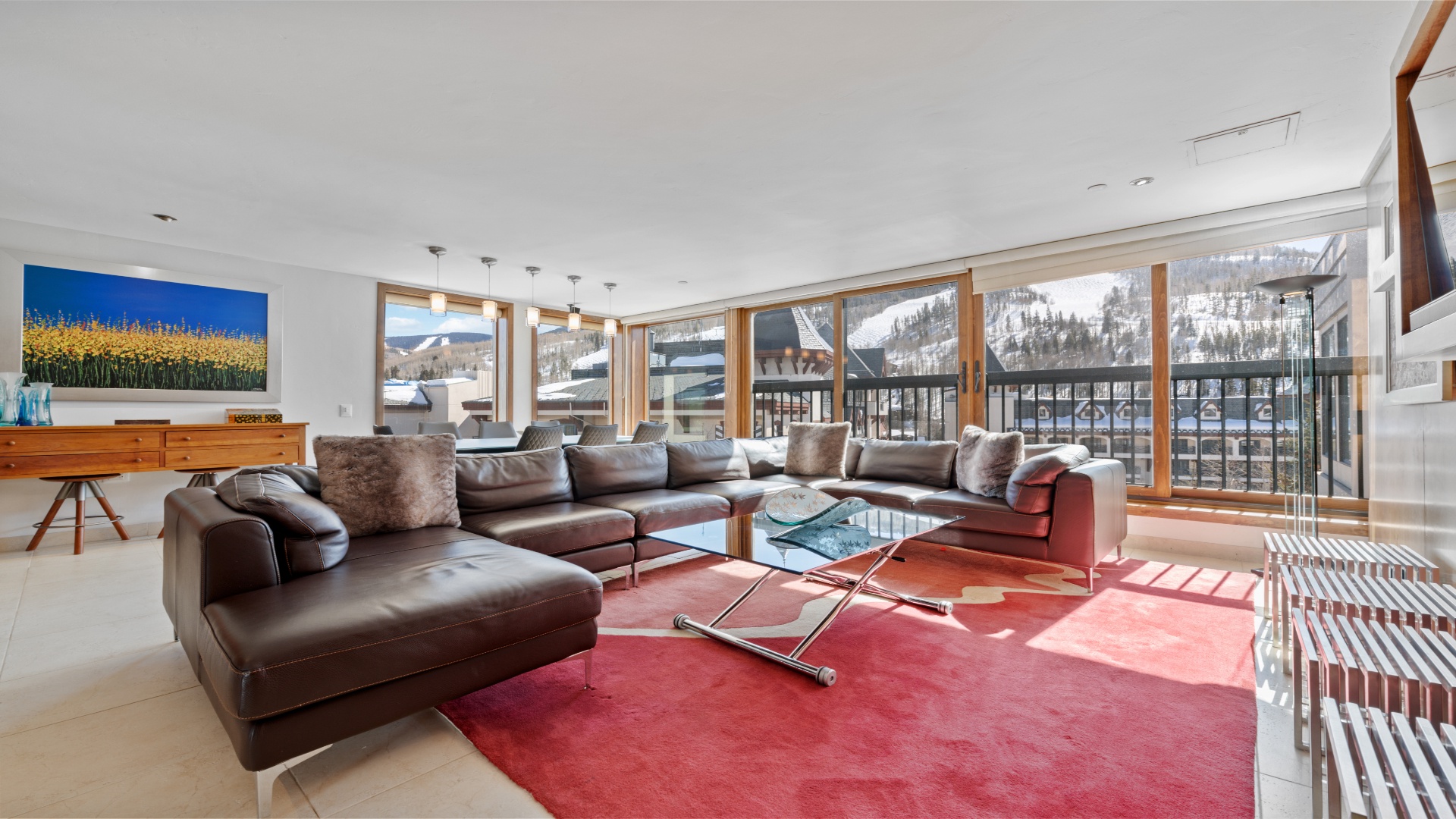 Settle into plush leather seating and soak in breathtaking mountain views through floor-to-ceiling windows. Your perfect alpine retreat awaits with modern comfort and stunning winter scenery.
