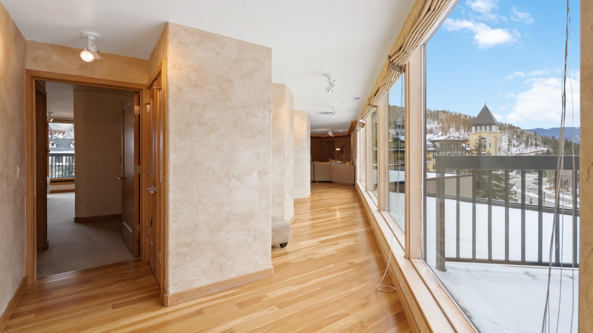 Sunlight floods through floor-to-ceiling windows, revealing snowy peaks and ski slopes just outside. Warm hardwood flows beneath your feet as you step into this bright, welcoming mountain retreat.