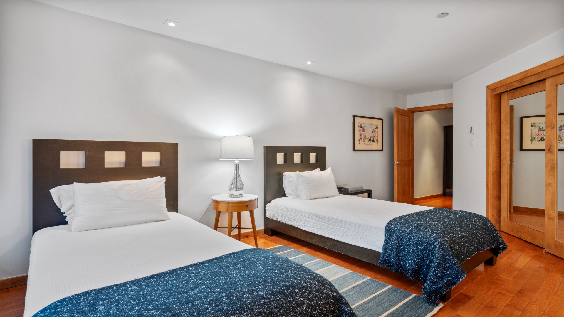 Rest easy in your thoughtfully designed bedroom, featuring two plush beds with crisp linens, warm wood accents, and soft lighting that creates a peaceful retreat after your day of adventure.