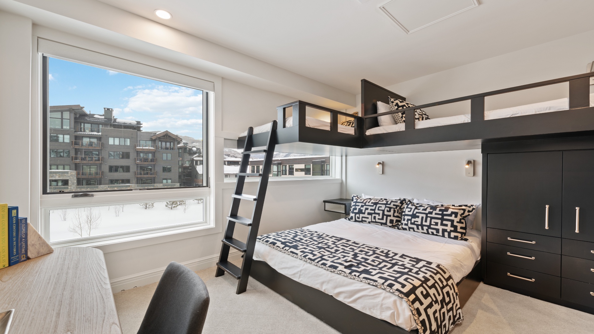 Your cozy mountain retreat features custom bunk beds with plush bedding, overlooking snowy slopes and village architecture—perfect for families or groups seeking comfort and adventure together.