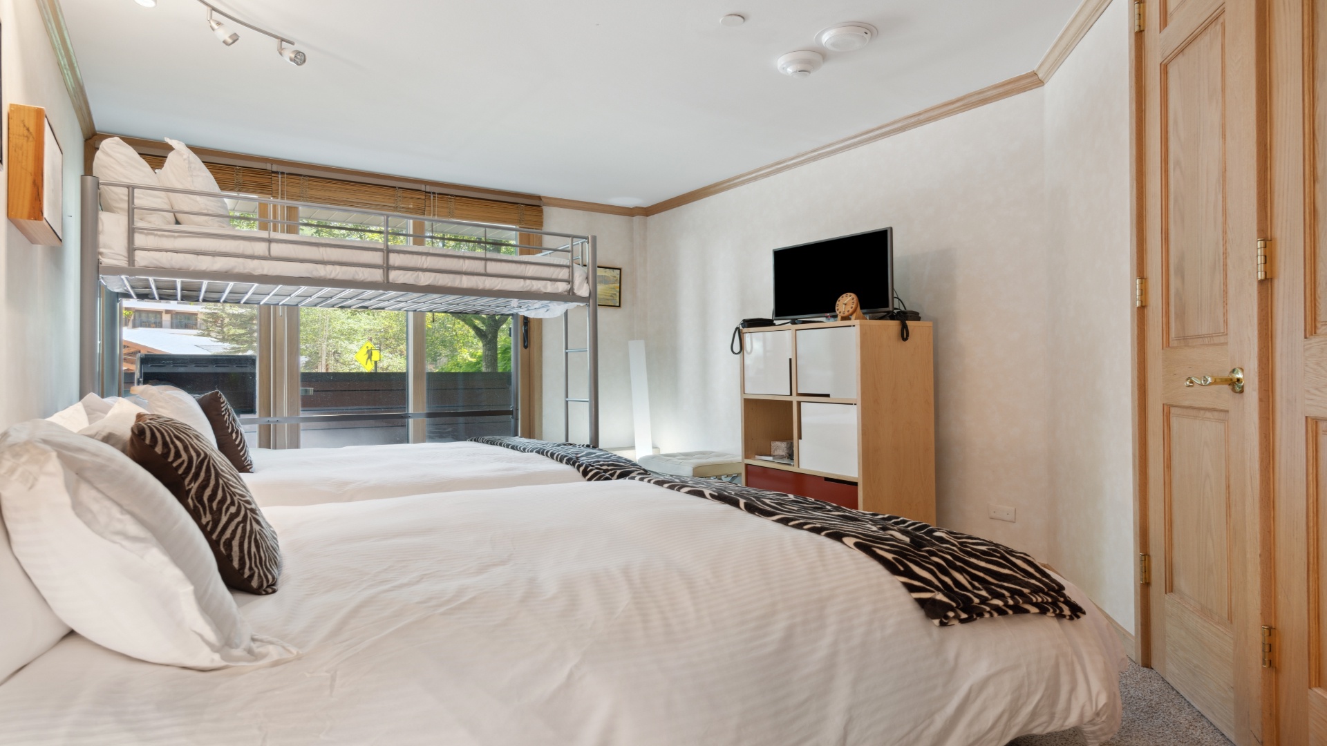 Unwind in your bright, spacious bedroom with plush bedding, a cozy bunk for extra guests, and thoughtful touches like a TV and storage wardrobe to make your stay comfortable.