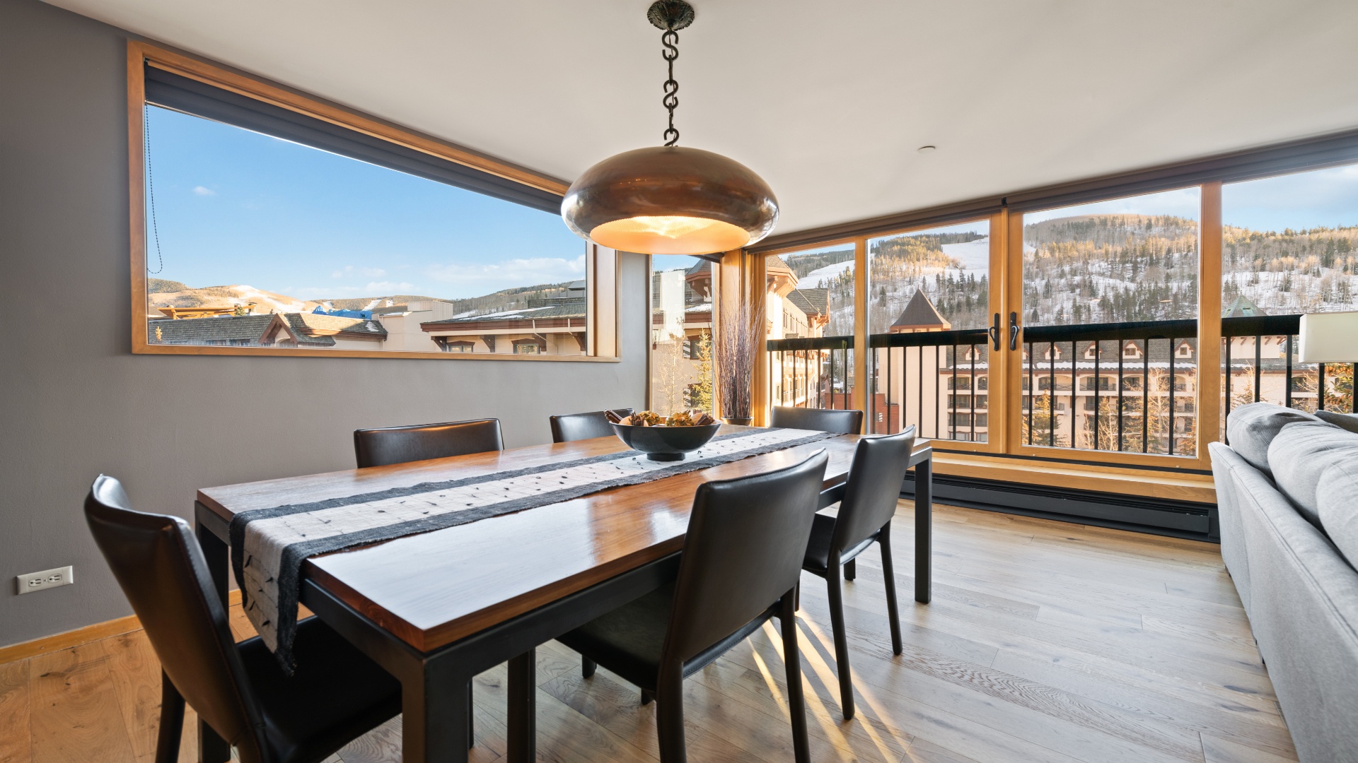 Gather around the dining table and soak in stunning mountain views through expansive windows framing the snowy slopes beyond. Natural light floods this inviting space, perfect for sharing meals after a day of adventure.
