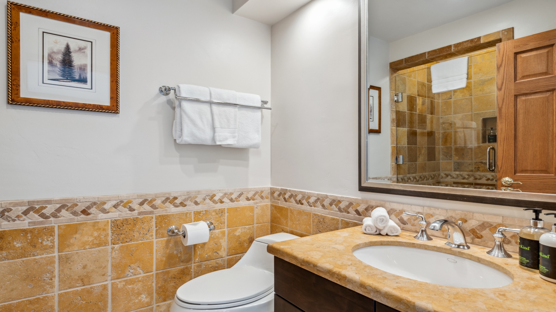 Step into your private bathroom with warm tile accents, a spacious glass-enclosed shower, and plush towels waiting for you after a long day of adventure.