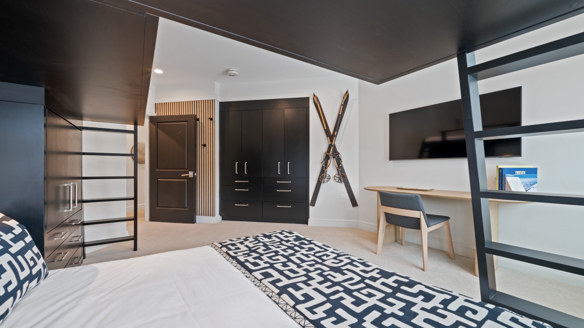 Your stylish retreat features a plush bed, sleek desk workspace, and thoughtful design touches like decorative skis and a dramatic dark ceiling that creates a cozy, alpine-inspired ambiance.