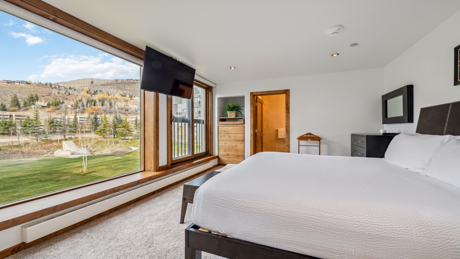 Wake up to stunning mountain and golf course views through expansive windows. Your peaceful bedroom features modern furnishings, plush bedding, and direct balcony access for fresh mountain air.