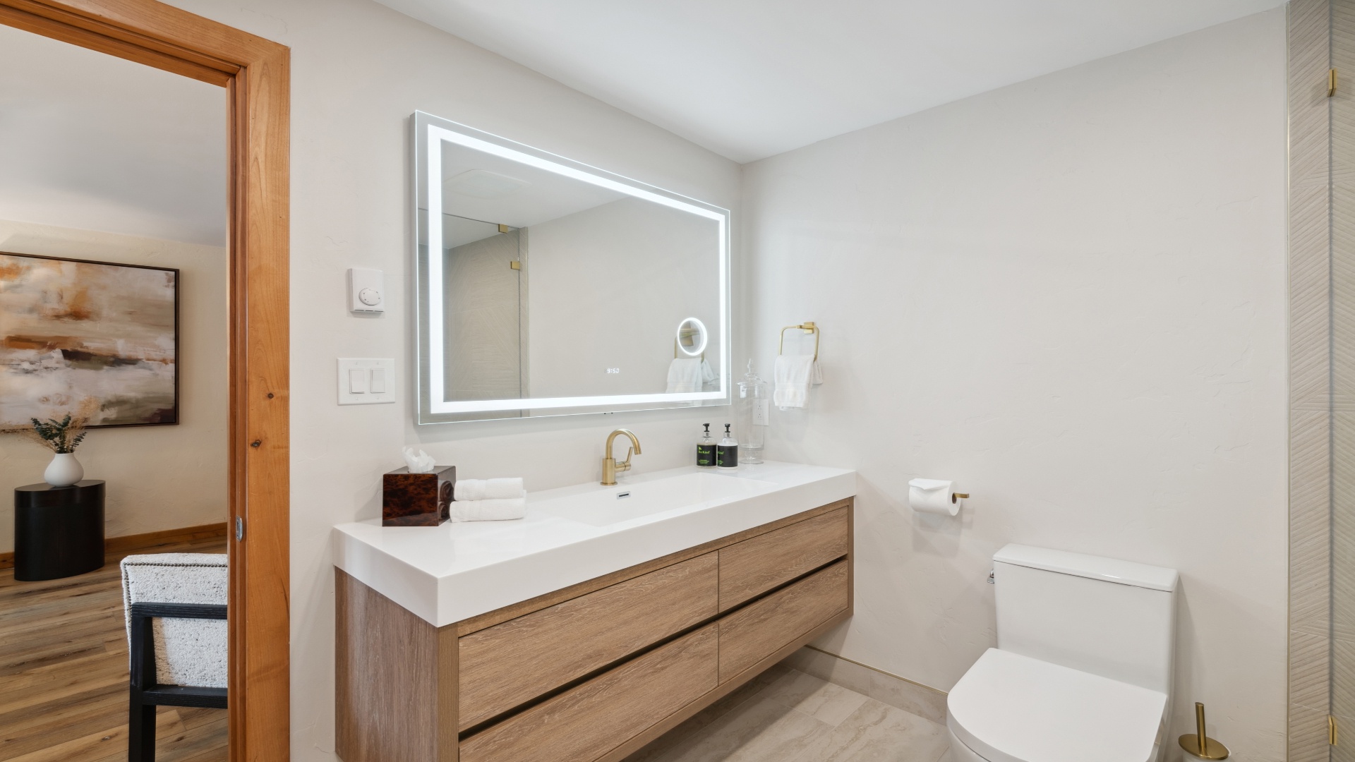 Step into your elegantly appointed bathroom, where warm wood tones meet crisp white surfaces. The LED-lit mirror and spacious vanity set a sophisticated, calming tone for your stay.