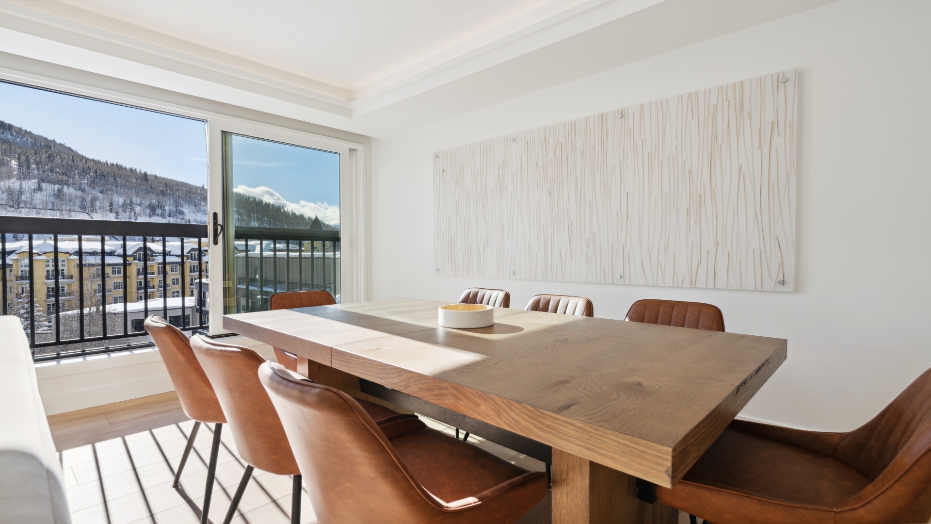 Gather around this sleek dining table and enjoy mountain views through your private balcony. The elegant space pairs contemporary design with warm wood tones, creating the perfect setting for memorable meals together.