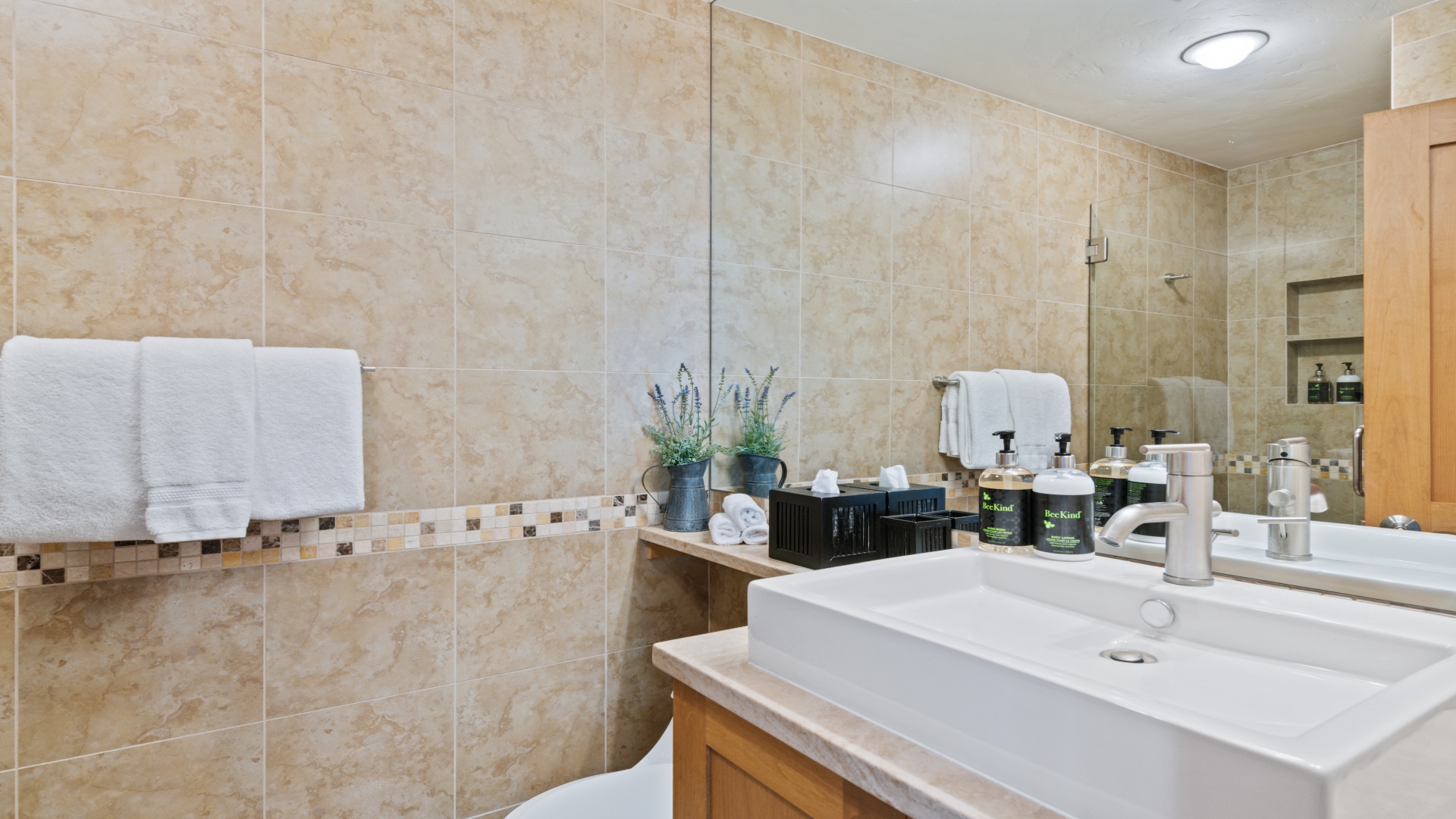 Step into your private spa-like bathroom with warm travertine tiles, plush towels, and premium amenities—a serene retreat awaiting your arrival.