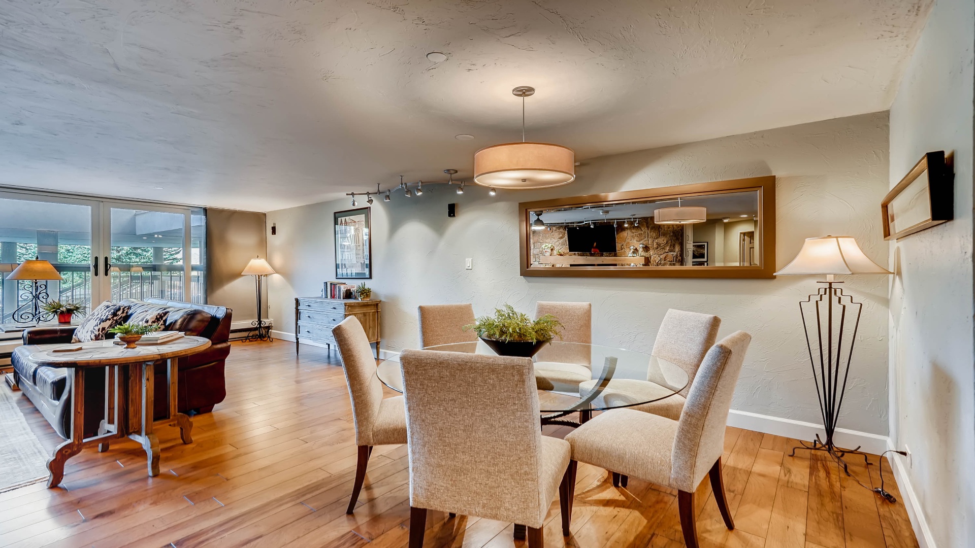 Step into your welcoming open-concept living space, where gleaming hardwood floors flow beneath elegant lighting and modern furnishings. Enjoy meals at the stylish glass dining table, then unwind on plush seating with a view.