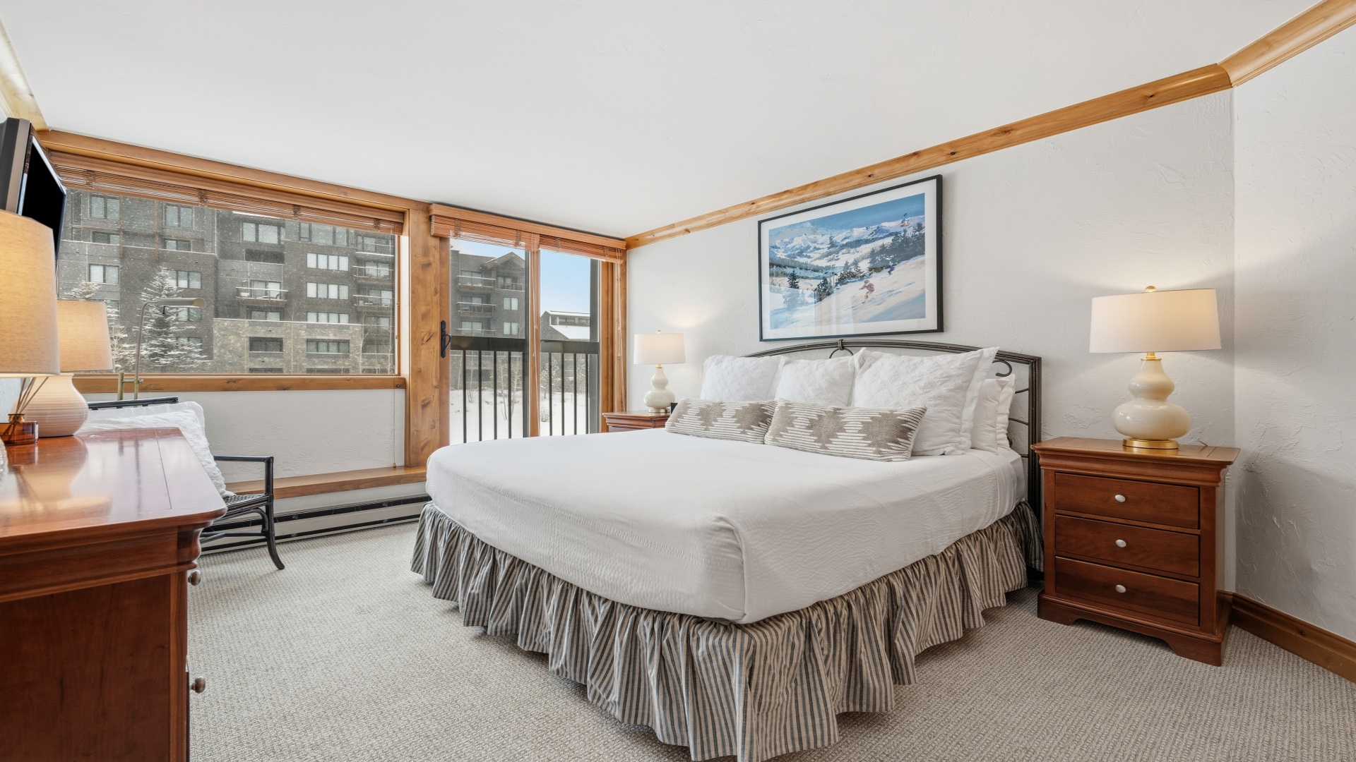 Unwind in your cozy bedroom with warm wood accents, a plush king bed, and mountain resort views through large windows—your perfect alpine retreat after a day of adventure.