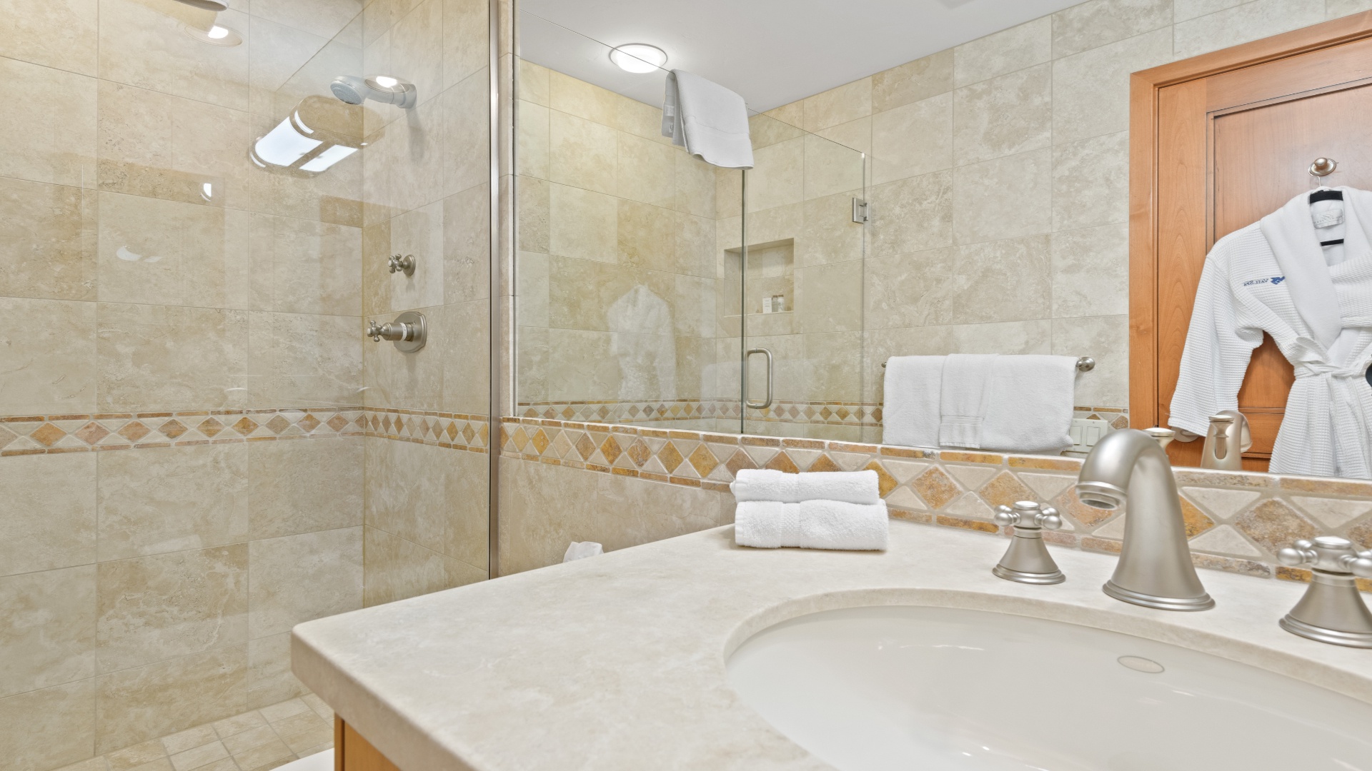 Step into your elegant bathroom with pristine marble accents, a walk-in glass shower, and plush white towels and robes waiting just for you.