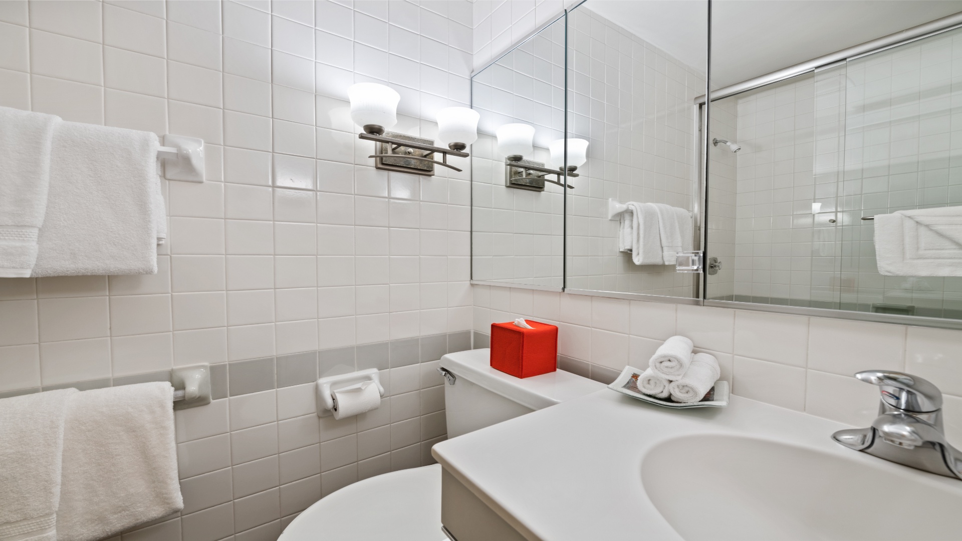 Freshen up in your bright, clean bathroom with crisp white tiles, a spacious vanity, and a glass-enclosed shower waiting for you.