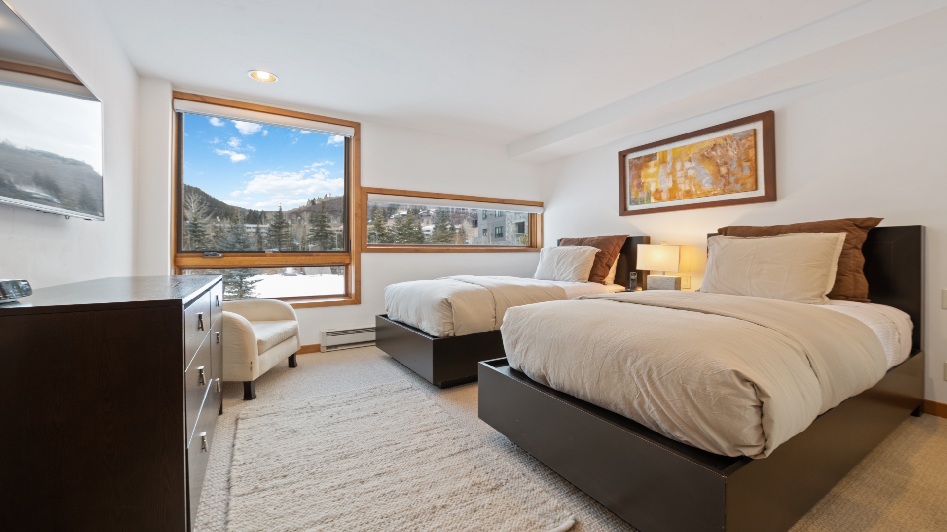 Wake up to stunning mountain views framed by large windows. Two plush beds invite restful sleep, while your private television and cozy seating ensure relaxation at every turn.