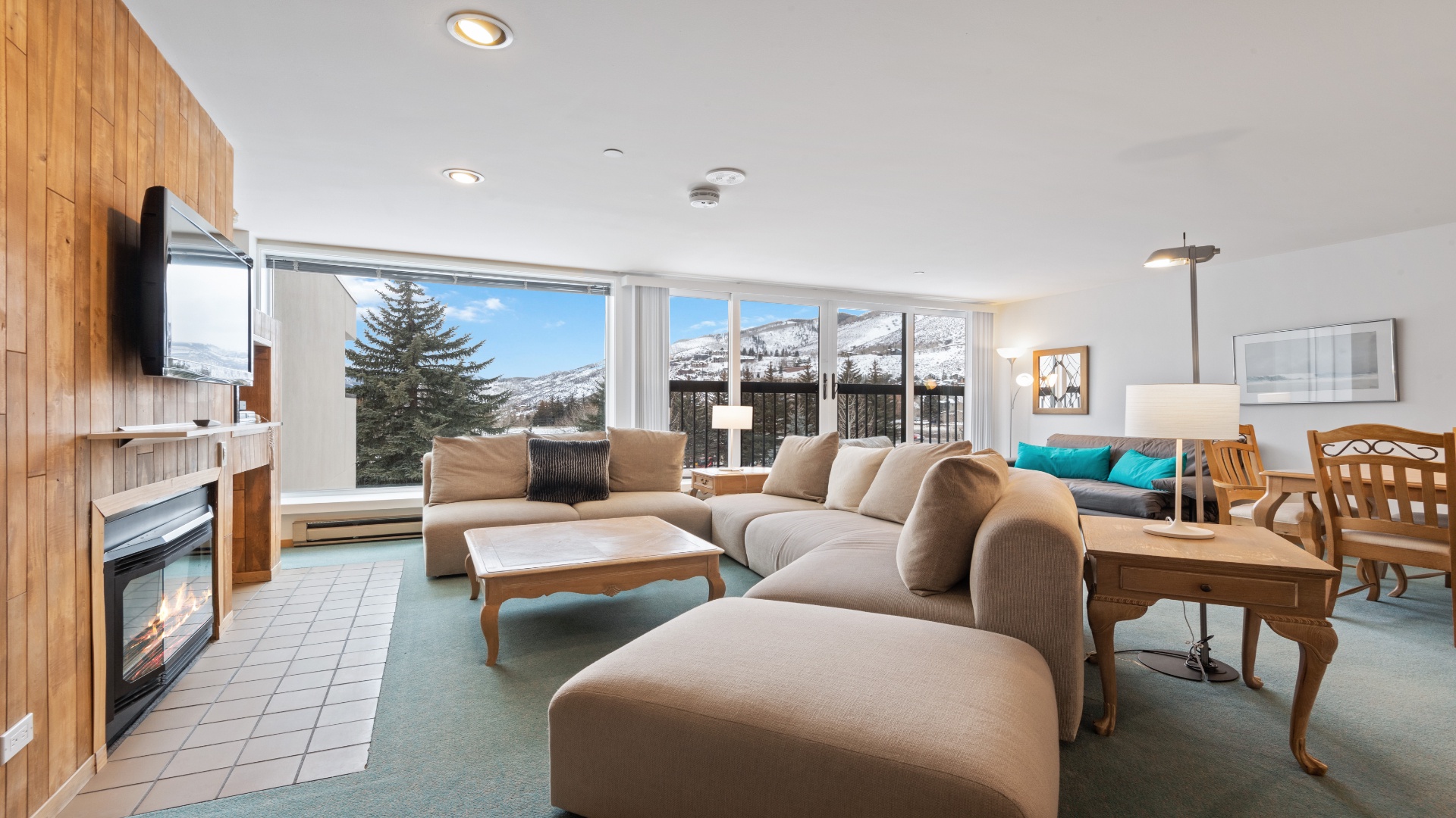 Imagine unwinding on plush seating while snow-capped mountains fill your view. The fireplace crackles beside you as natural light floods this cozy, open-concept retreat—your perfect mountain getaway.