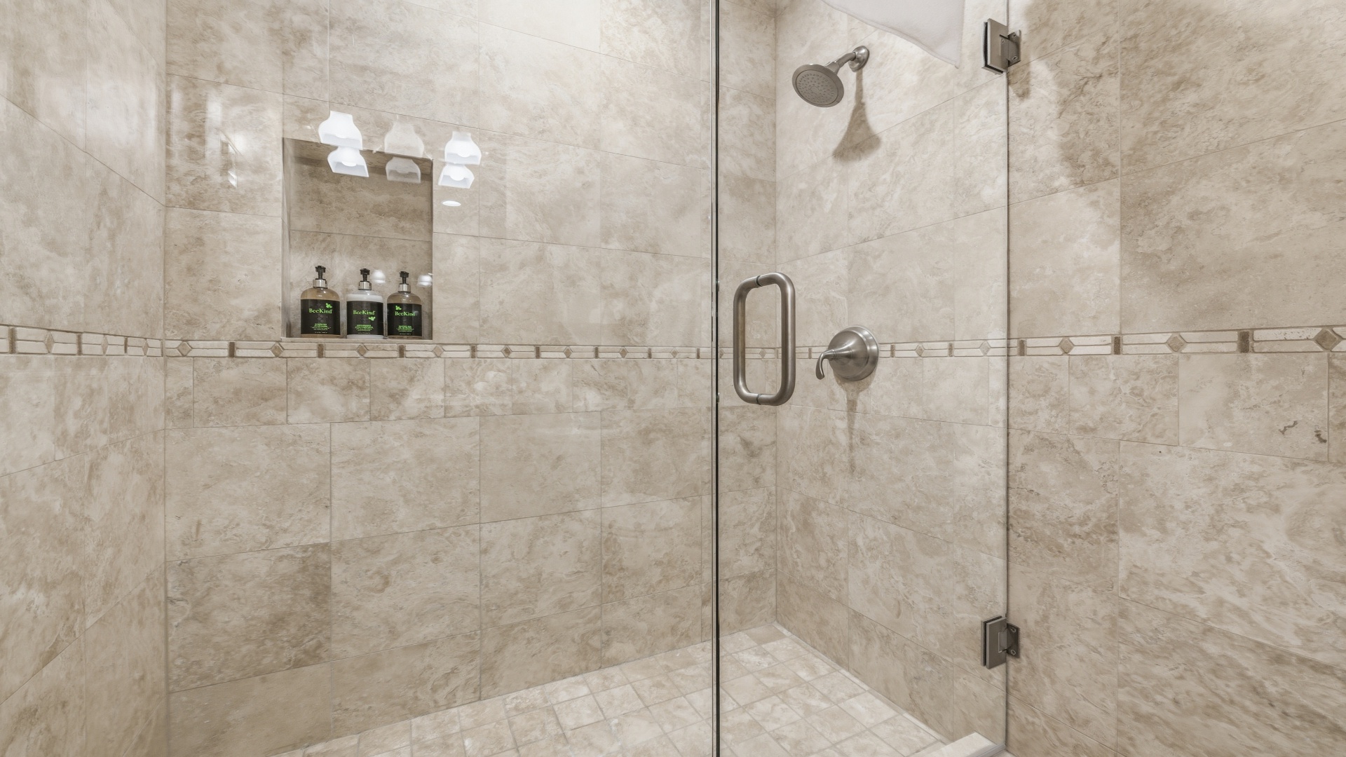 Step into your elegant walk-in shower, where rainfall flows and premium toiletries await in a spa-like sanctuary of natural stone and glass.