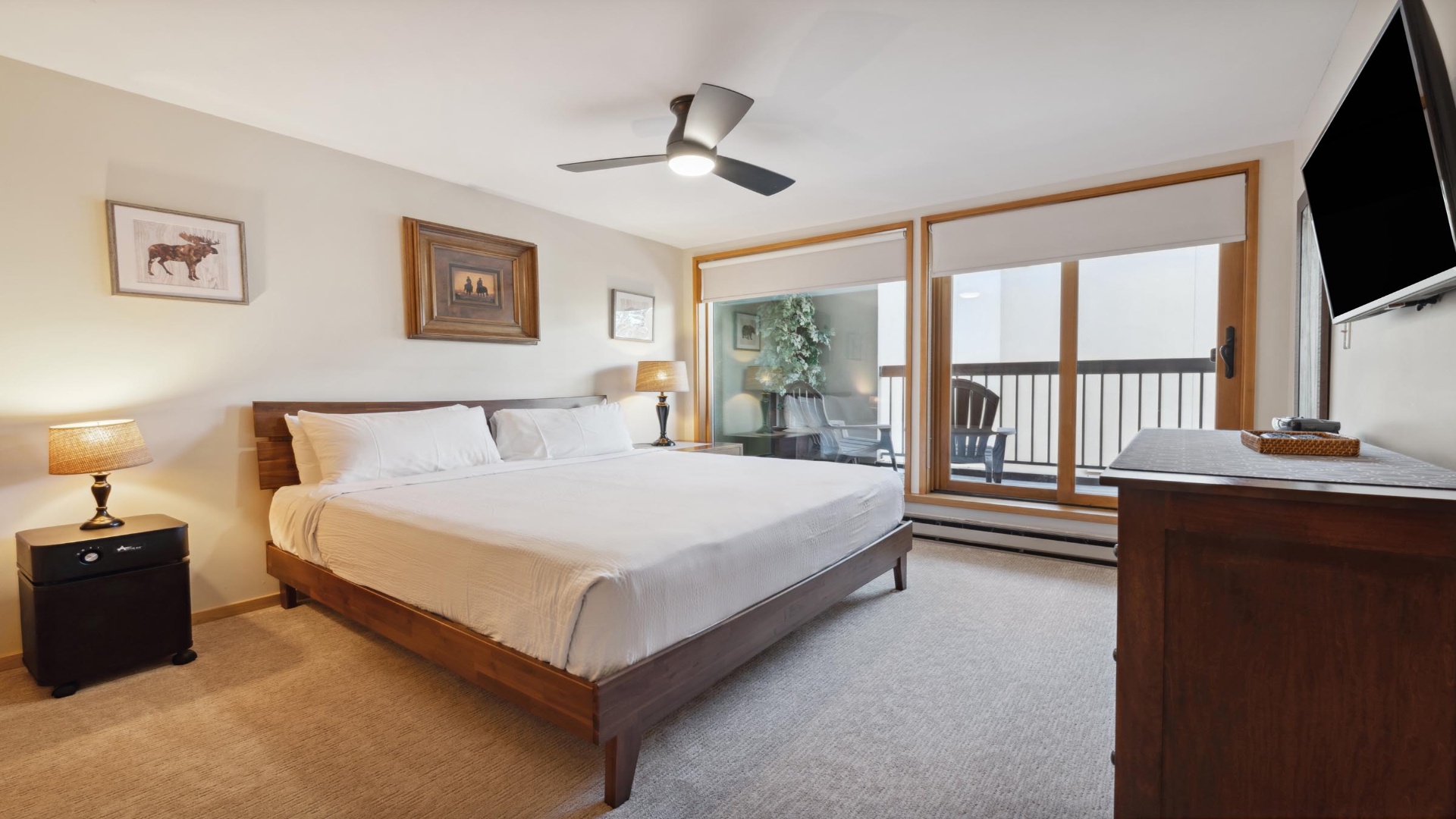 Your serene bedroom features a plush king bed, ceiling fan, private balcony, and wall-mounted TV—your peaceful retreat after a day of adventure.