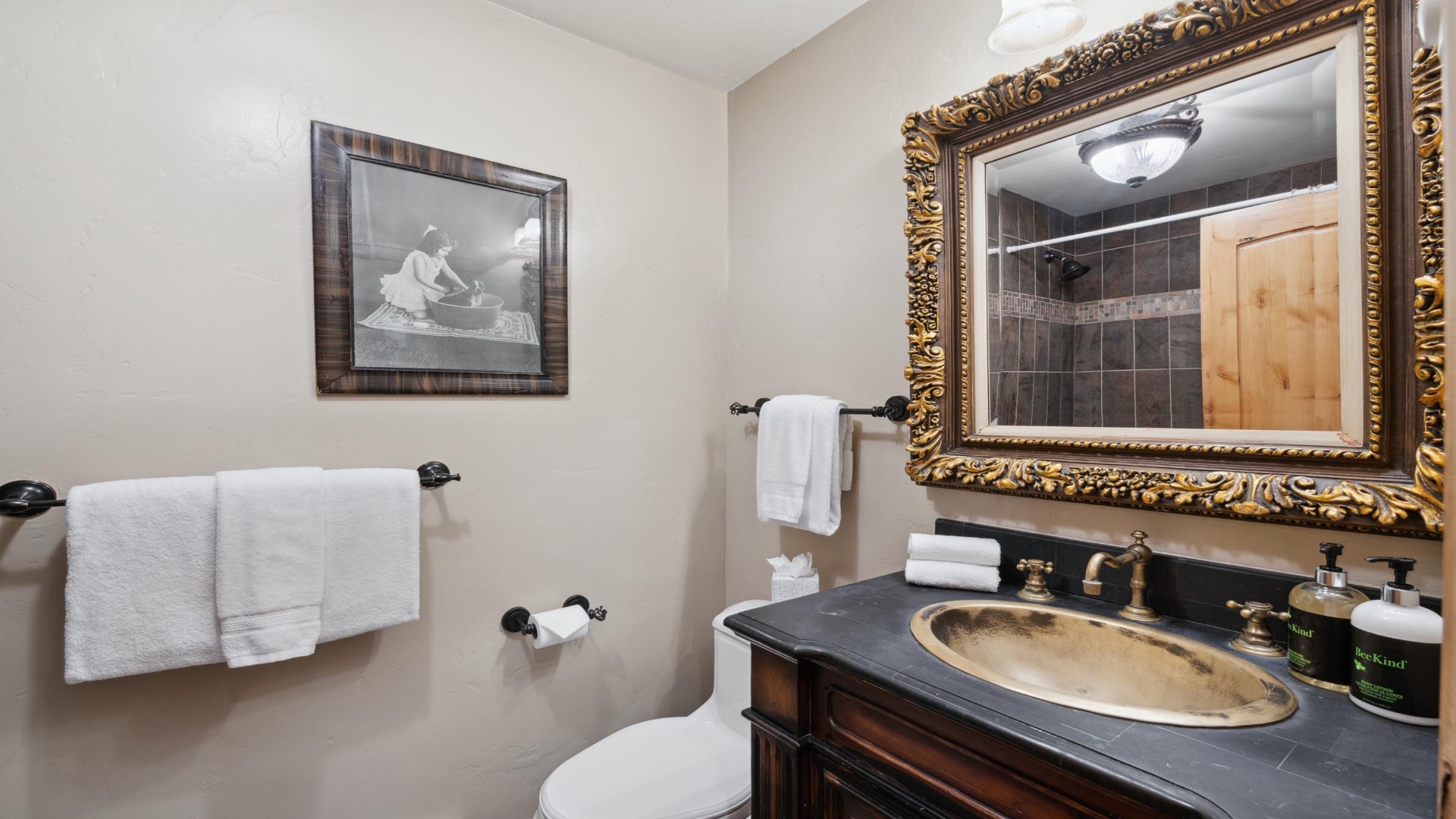 Step into your private bathroom where plush white towels await. The elegant vanity and ornate mirror frame create a refined retreat for freshening up after a day of adventure.