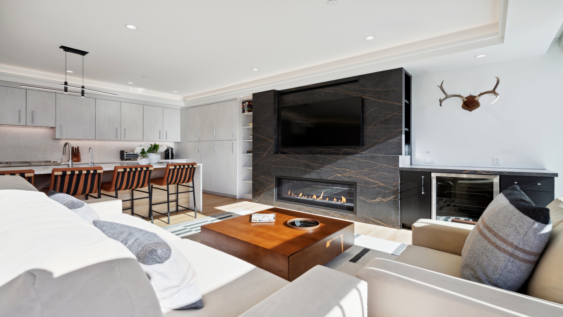 Settle into your open-concept retreat where a striking stone fireplace anchors the living space, modern barstools line the kitchen island, and natural light highlights every sleek surface.