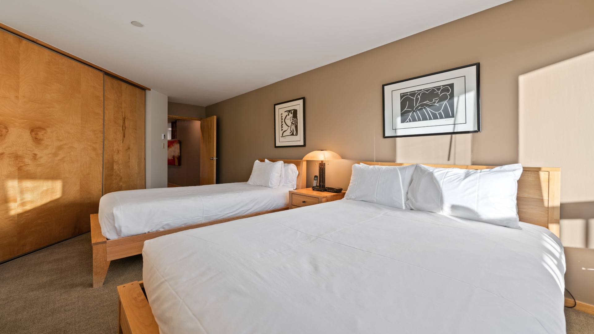 Drift off in crisp linens and wake refreshed. Your room features two plush beds, warm lighting, and modern artwork for a peaceful retreat.