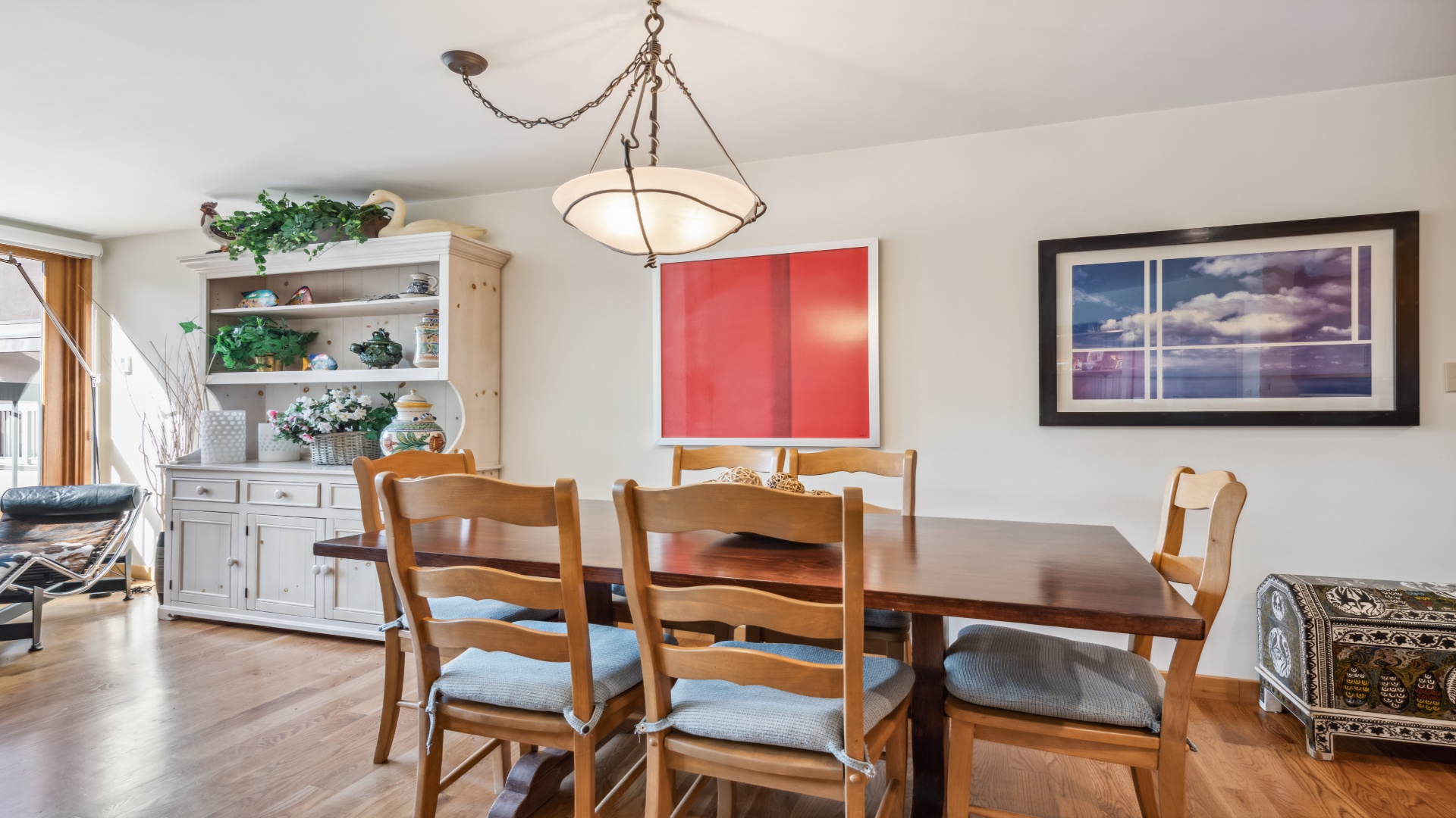 Gather around the warm wood dining table for home-cooked meals or morning coffee. The open layout and elegant chandelier create an inviting atmosphere for your group to connect and relax together.