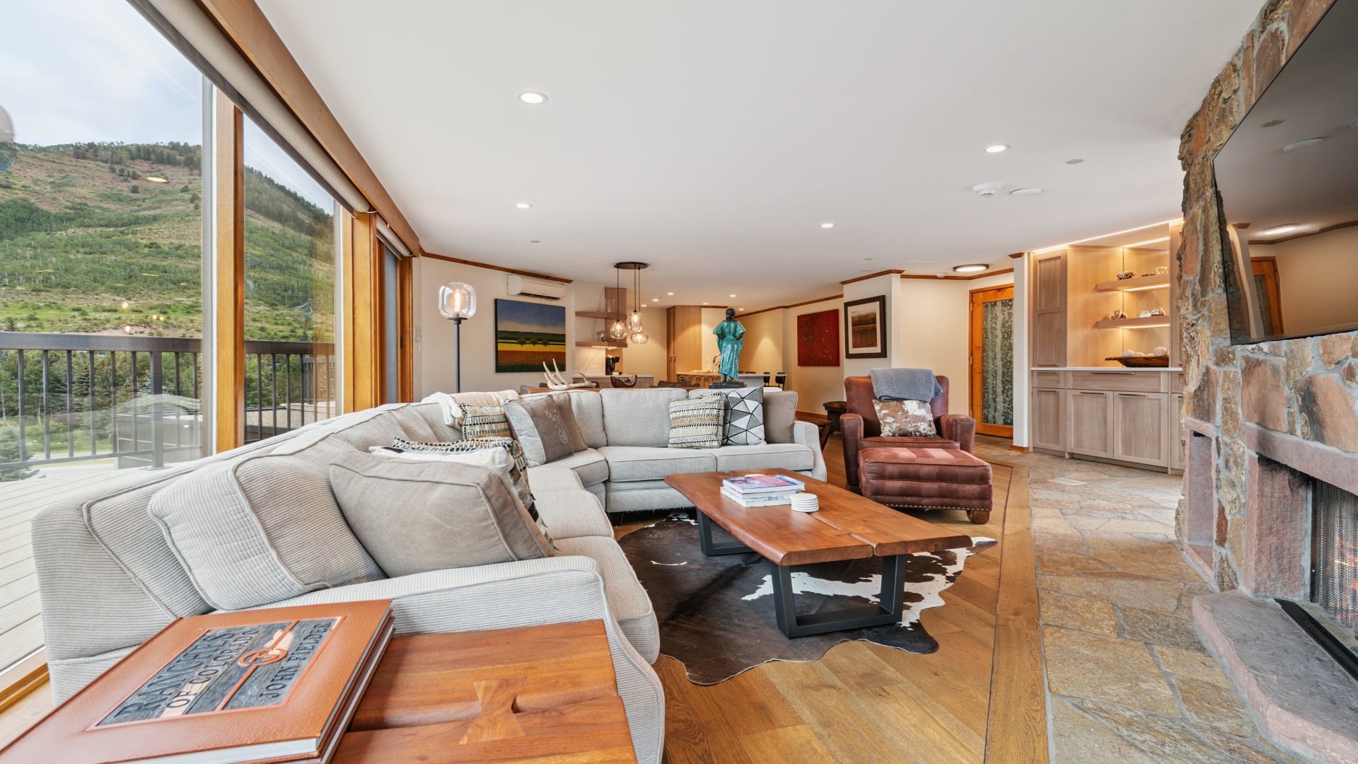 Sink into plush seating and take in sweeping mountain vistas through floor-to-ceiling windows. Warm wood accents, stone fireplace, and elegant furnishings create your perfect mountain retreat.