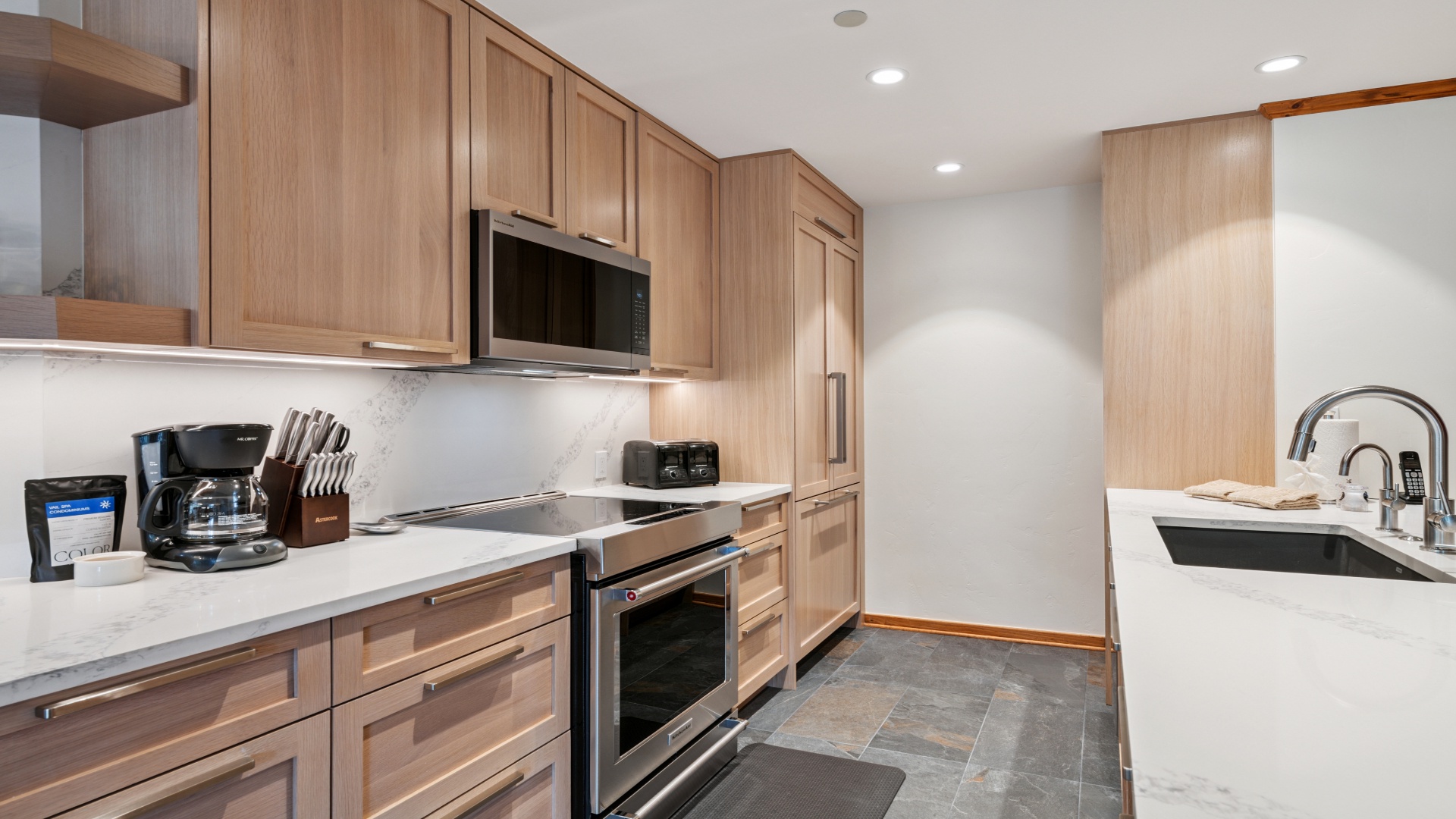 Your fully equipped kitchen features sleek appliances, warm wood cabinetry, and gleaming countertops—perfect for preparing everything from morning coffee to memorable home-cooked meals during your stay.