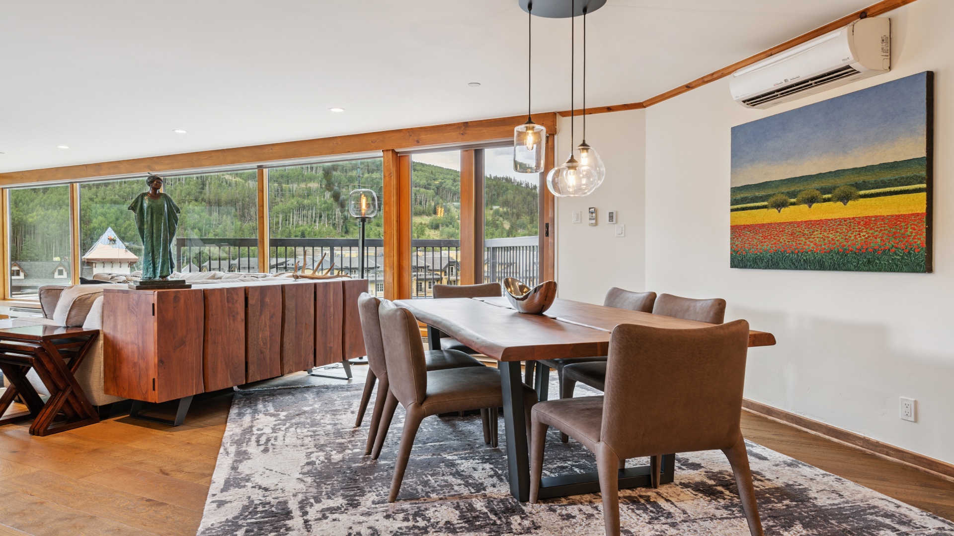 Gather around this elegant dining table where natural light pours through expansive windows, framing stunning mountain views while you share meals and create memories together.