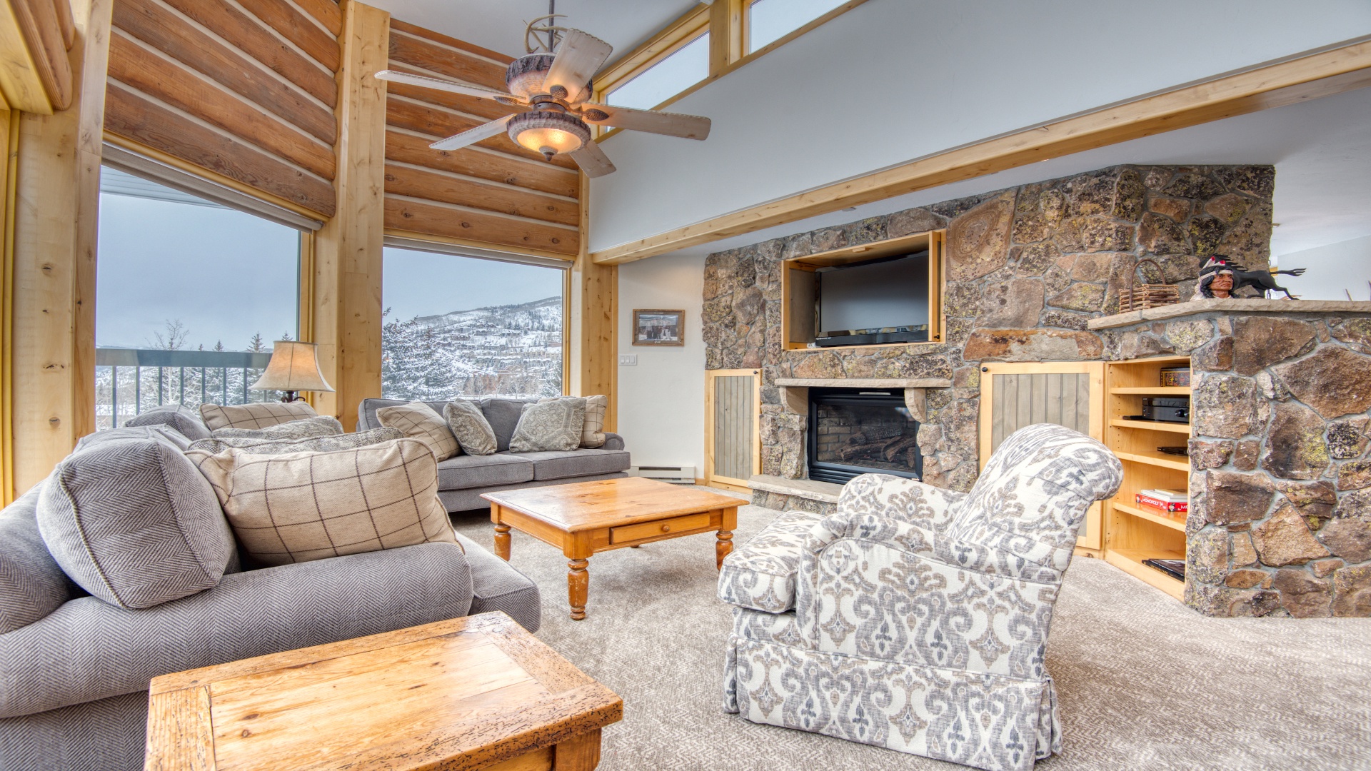 Unwind in your spacious living room where plush seating, a warm stone fireplace, and sweeping mountain views create the perfect retreat after a day of adventure.