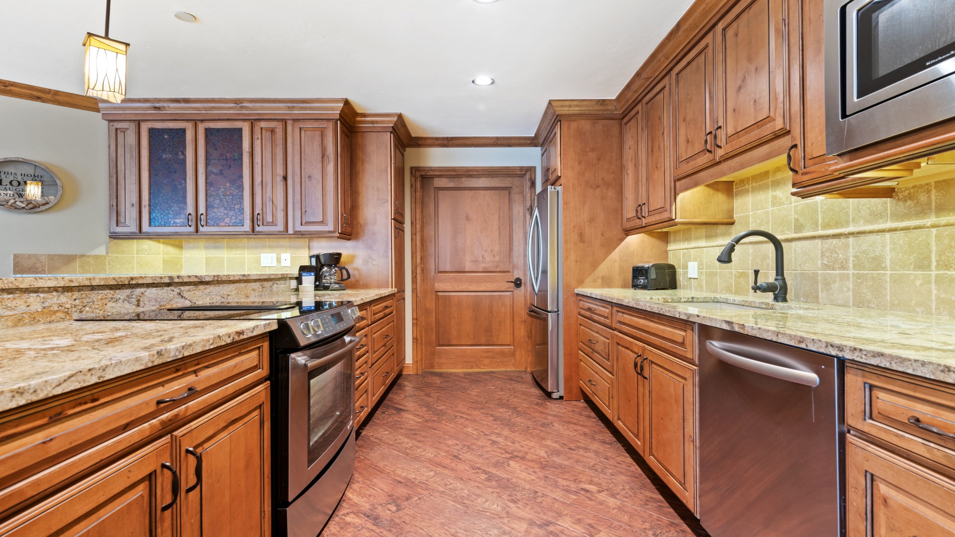 Picture yourself preparing meals in this spacious, fully equipped kitchen featuring rich wood cabinetry, granite countertops, and modern stainless steel appliances—perfect for your mountain getaway.