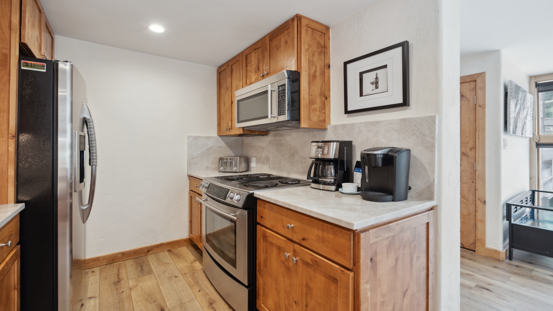 Your fully equipped kitchen features warm wood cabinetry, stainless steel appliances, and a coffee station ready to fuel your mornings.