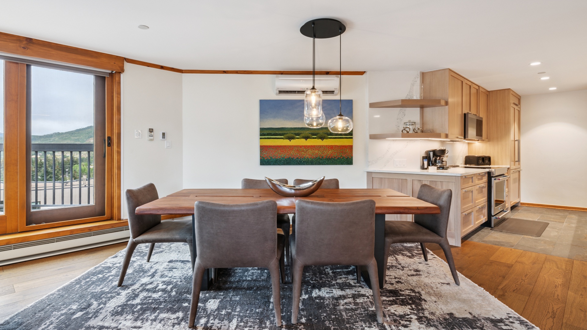 Gather around the warm wood table and enjoy mountain views through your private balcony door. The open kitchen invites effortless entertaining, complete with modern appliances and sleek cabinetry.