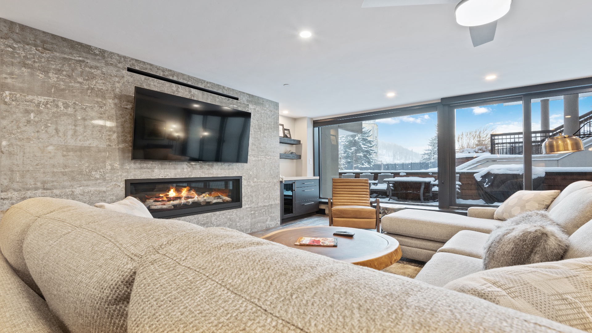 Sink into plush seating by the crackling fireplace as you gaze out at snowy mountain vistas through floor-to-ceiling windows—your perfect alpine retreat awaits.