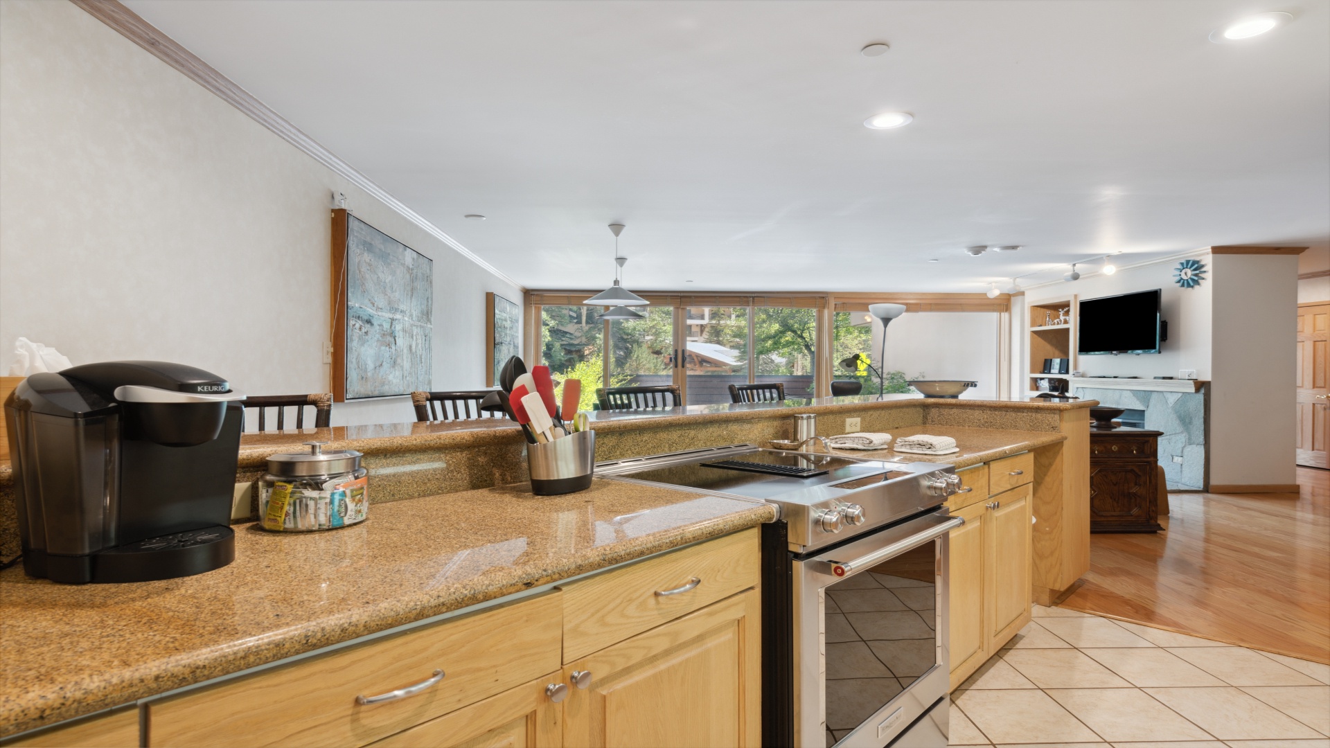 Your spacious kitchen features warm wood cabinetry, gleaming granite countertops, and stainless steel appliances, all bathed in natural light from large windows framing serene garden views.