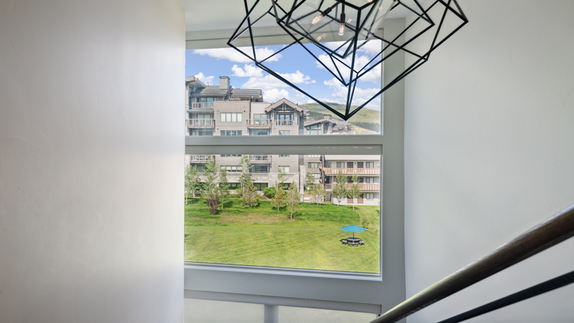 A peaceful green courtyard framed by mountain-view residences, visible from inside the property. Modern art adds a creative touch to the bright, airy interior.
