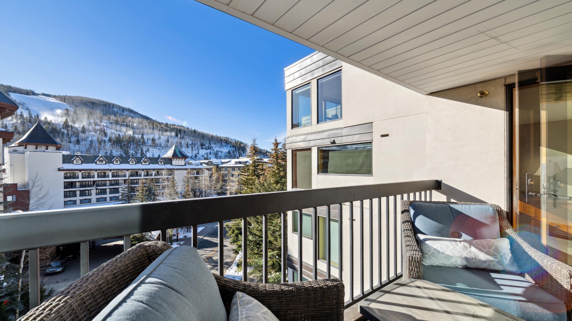 Scenic mountain views frame this cozy balcony, offering a peaceful retreat amidst a picturesque alpine village and snow-dusted peaks.