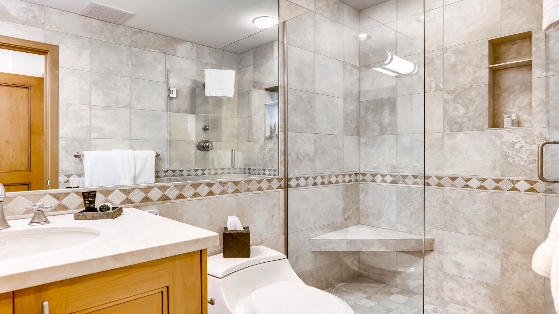 Your private bathroom features elegant marble tiling, a spacious glass-enclosed shower with built-in seating, and fresh towels waiting for you to unwind after a day of adventure.